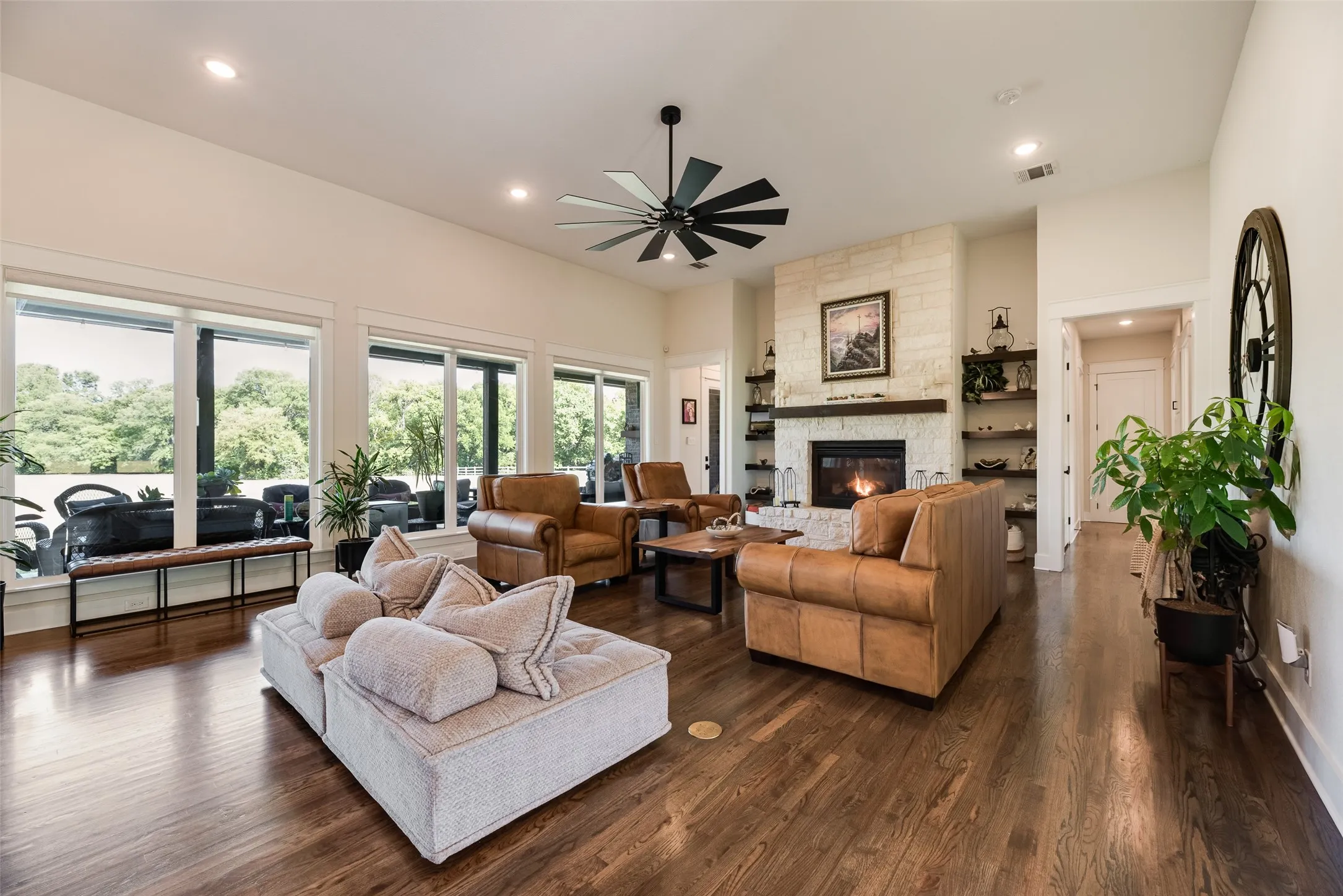 Spacious living area featuring rich wood-finish flooring, a stone-clad fireplace with a wood mantel, and built-in shelving