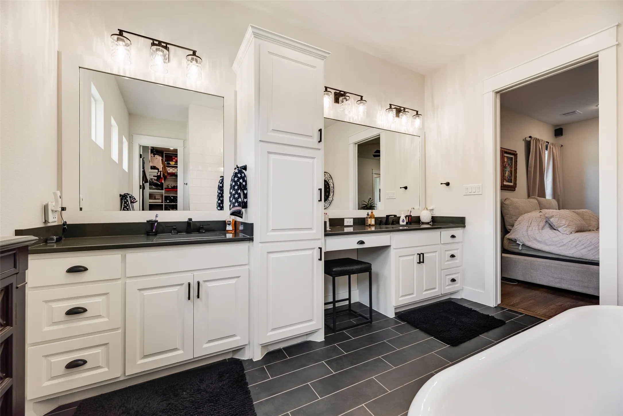 Dual vanity with white cabinetry, dark countertops, and matte black hardware