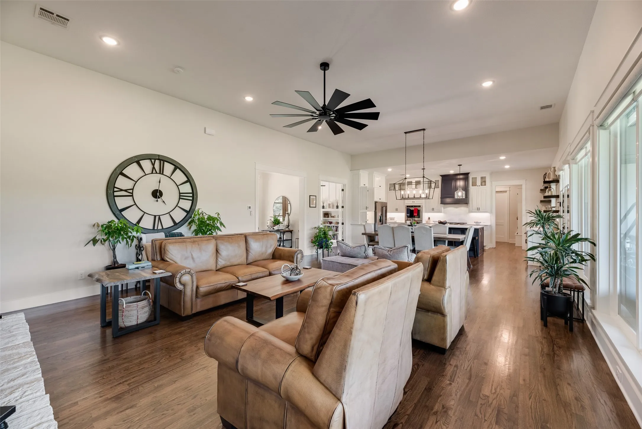 Expansive open-concept living area featuring rich wood-finish flooring, recessed lighting, and a modern ceiling fan
