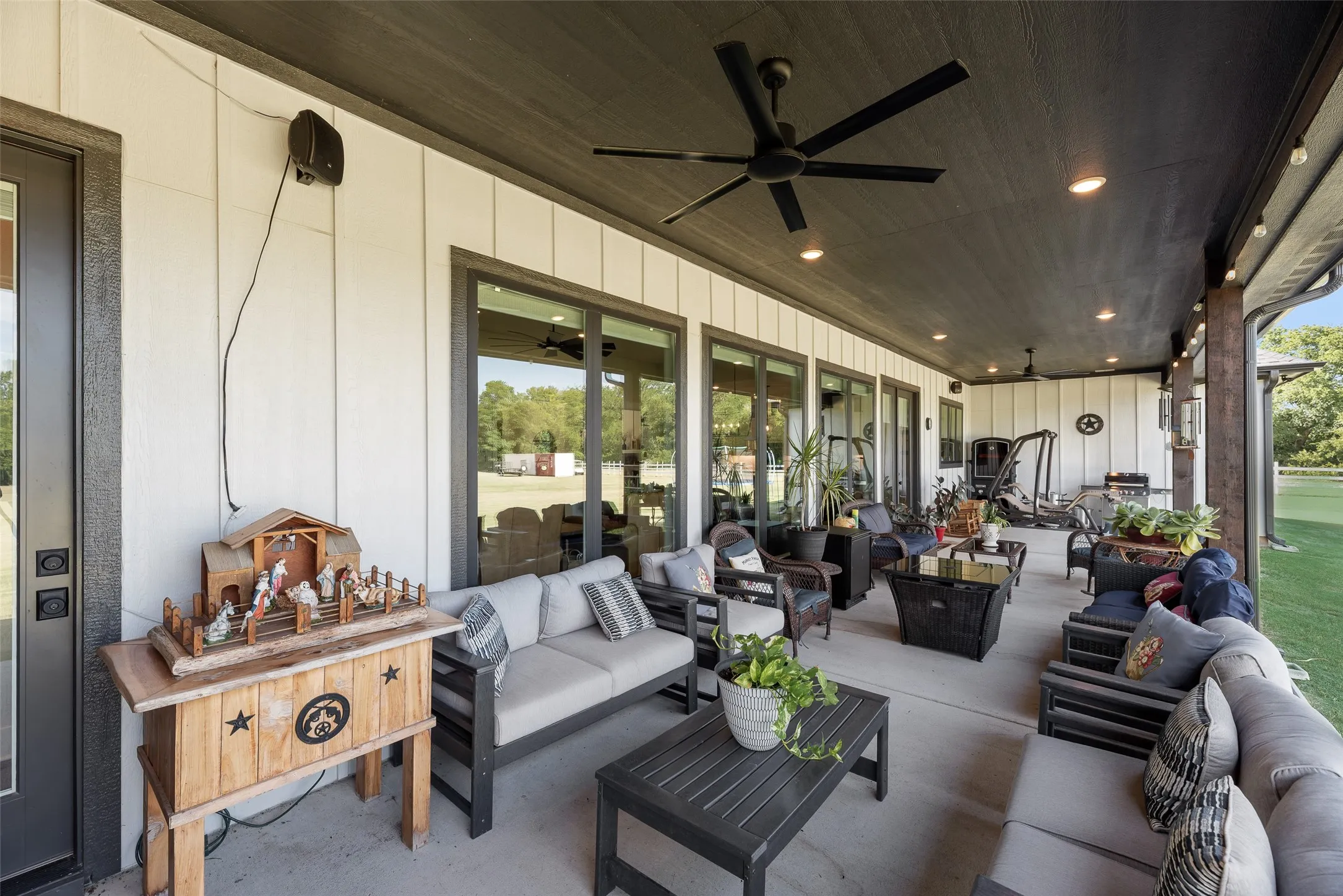 Expansive covered patio featuring a dark wood-finish ceiling, multiple recessed lights, and two ceiling fans