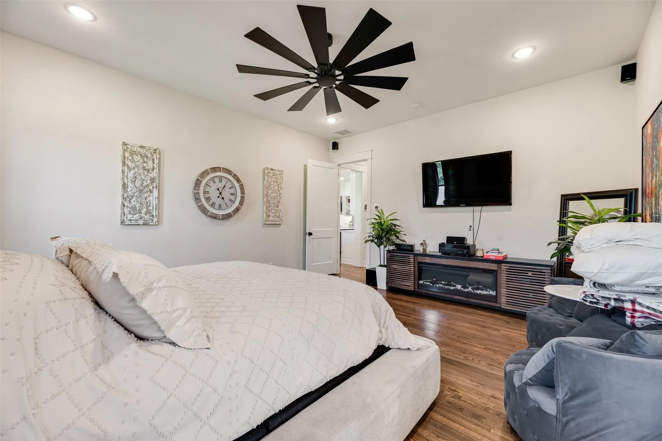 Recessed lighting illuminates this room featuring wood-finish flooring and a contemporary ceiling fan