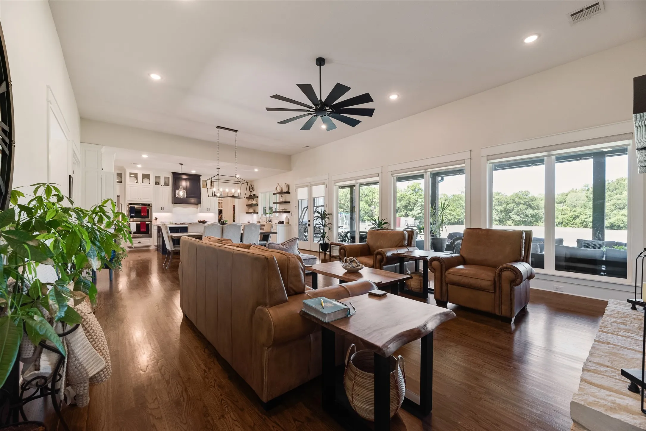 Spacious open-concept living area featuring rich wood-finish flooring, a contemporary ceiling fan, and recessed lighting