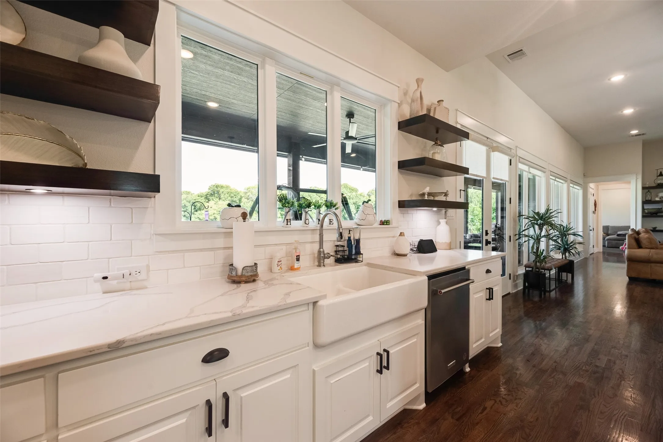 Kitchen with white cabinetry, a farmhouse sink, light-toned countertops, and a subway tile backsplash