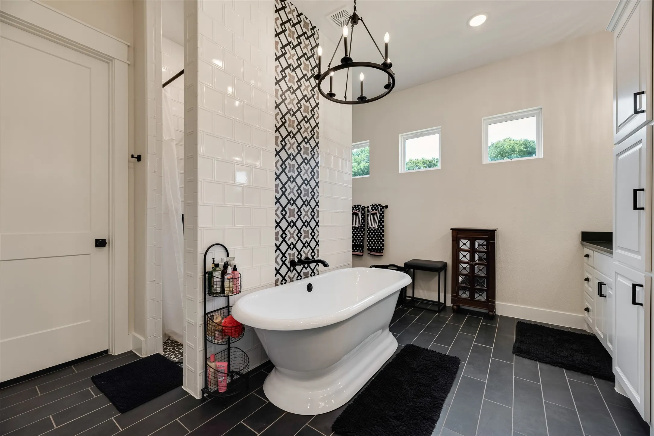 Freestanding soaking tub with dark-toned fixtures, set against a patterned accent tile wall