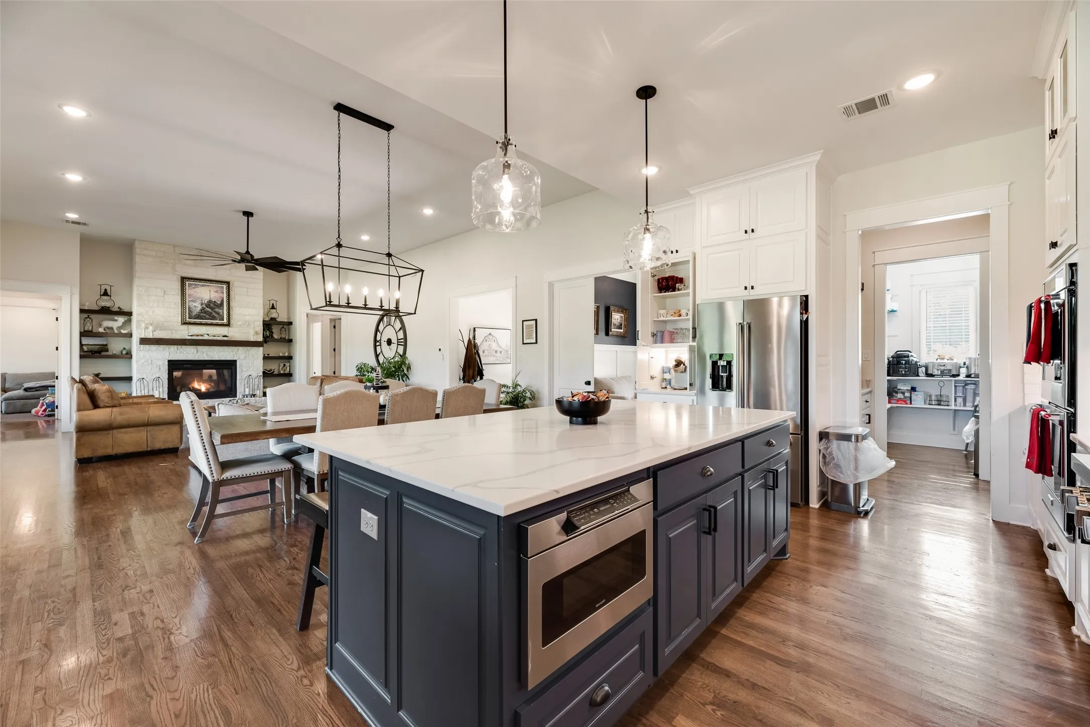 Spacious kitchen island featuring a light-toned countertop, dark-toned cabinetry, and an integrated microwave