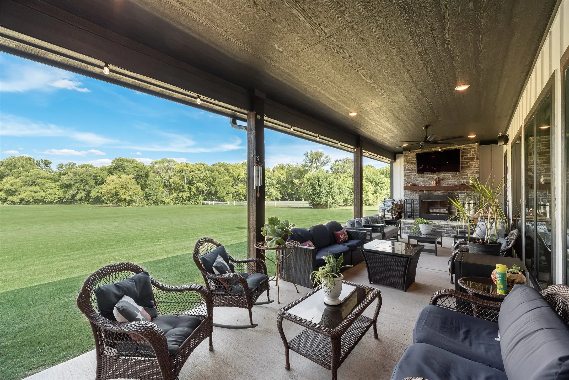 Covered patio featuring a stone-clad fireplace, integrated ceiling fan, recessed lighting, and a concrete slab floor