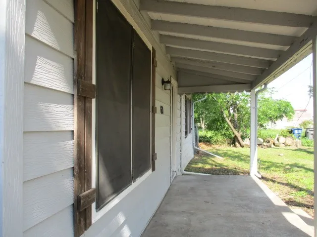 Covered front porch with concrete flooring and exposed rafters