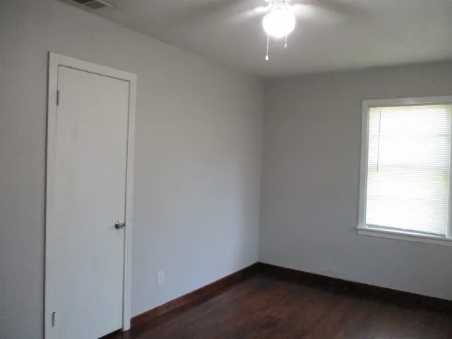 Room featuring light gray walls, dark wood-finish flooring, and white baseboards