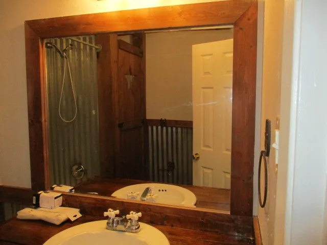 Bathroom vanity with dual white porcelain drop-in sinks and rustic wood-finish countertop