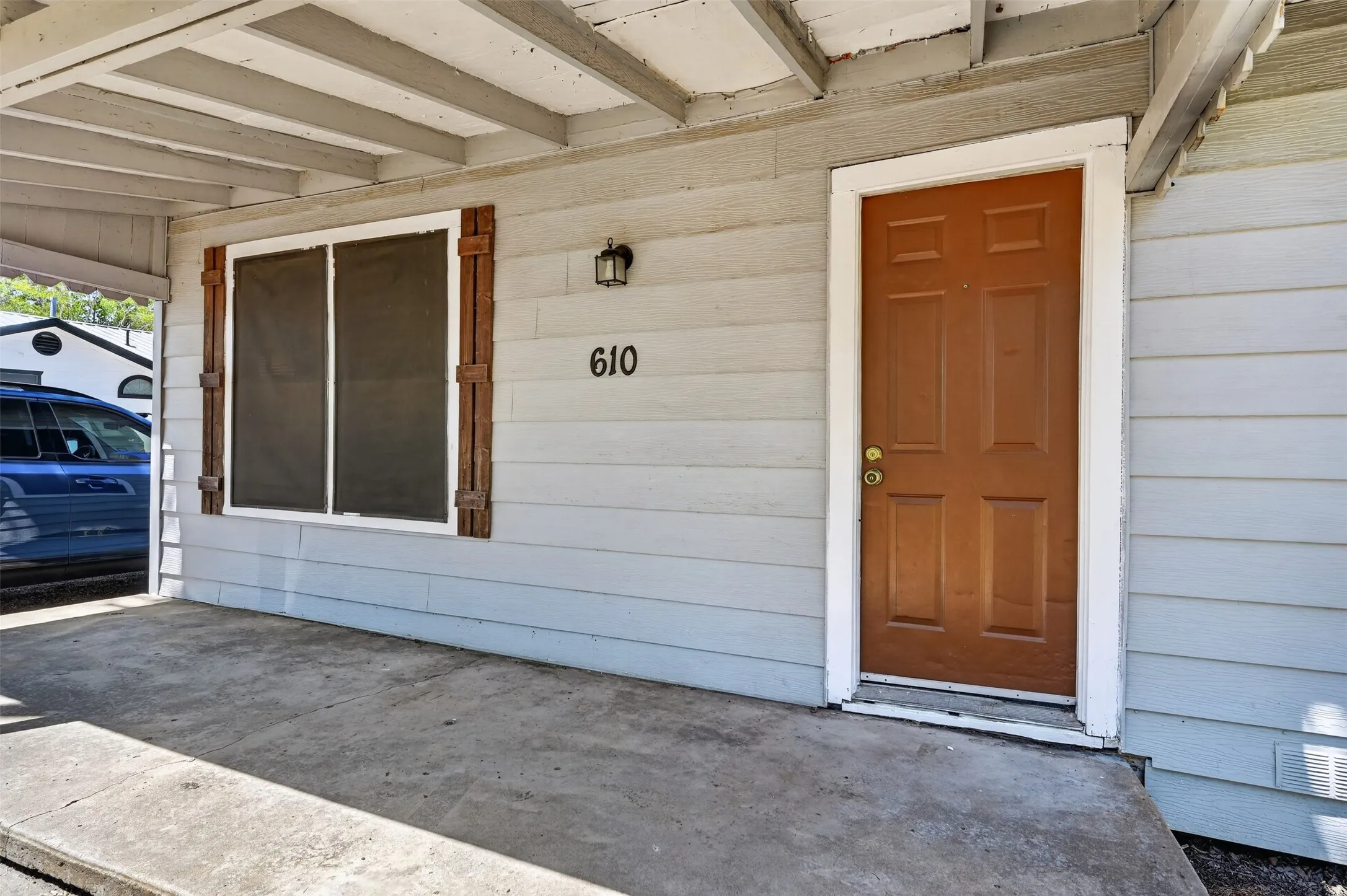 Covered entry with concrete flooring, wood siding, and exterior wall lantern