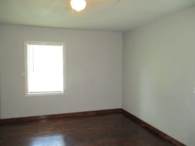 Room featuring light-toned walls, dark wood-finish flooring, and a white-framed window