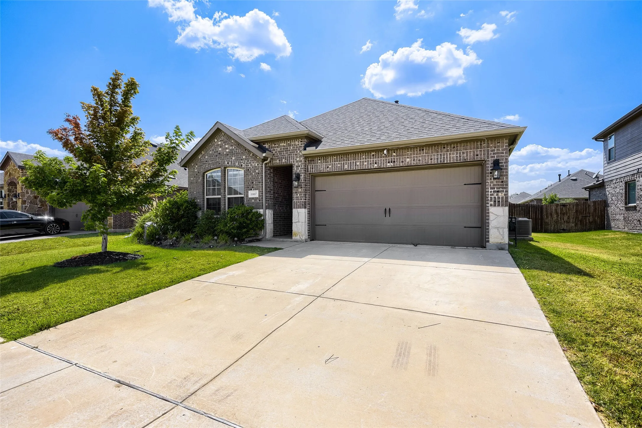 Brick veneer exterior with stone accents and a gray shingle roof