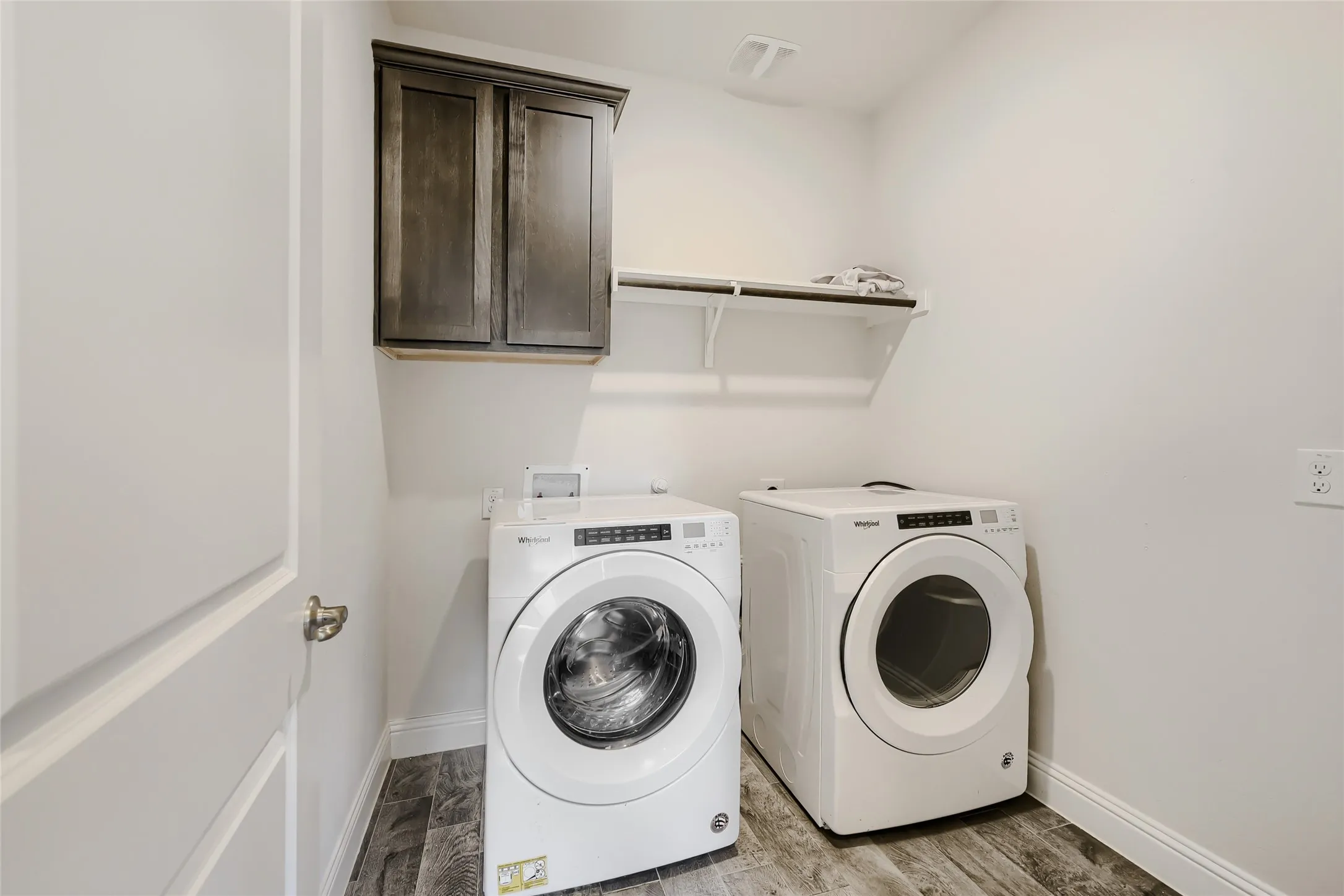 Laundry area with wood-finish flooring, white walls, and white trim