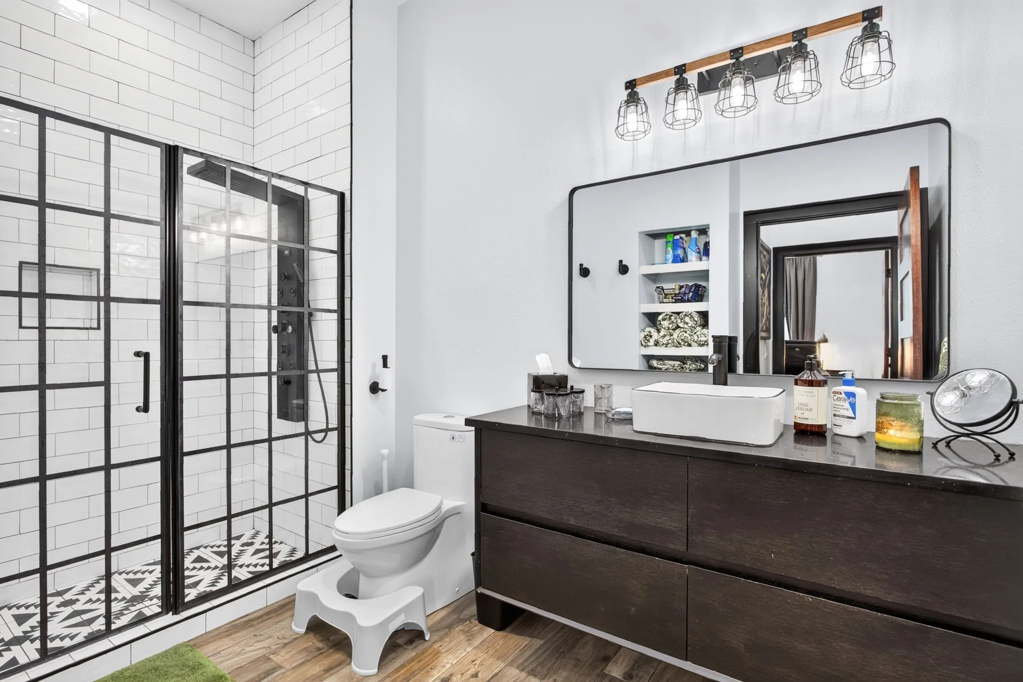 Modern bathroom featuring a black grid-patterned shower enclosure with subway tile surround and a patterned floor