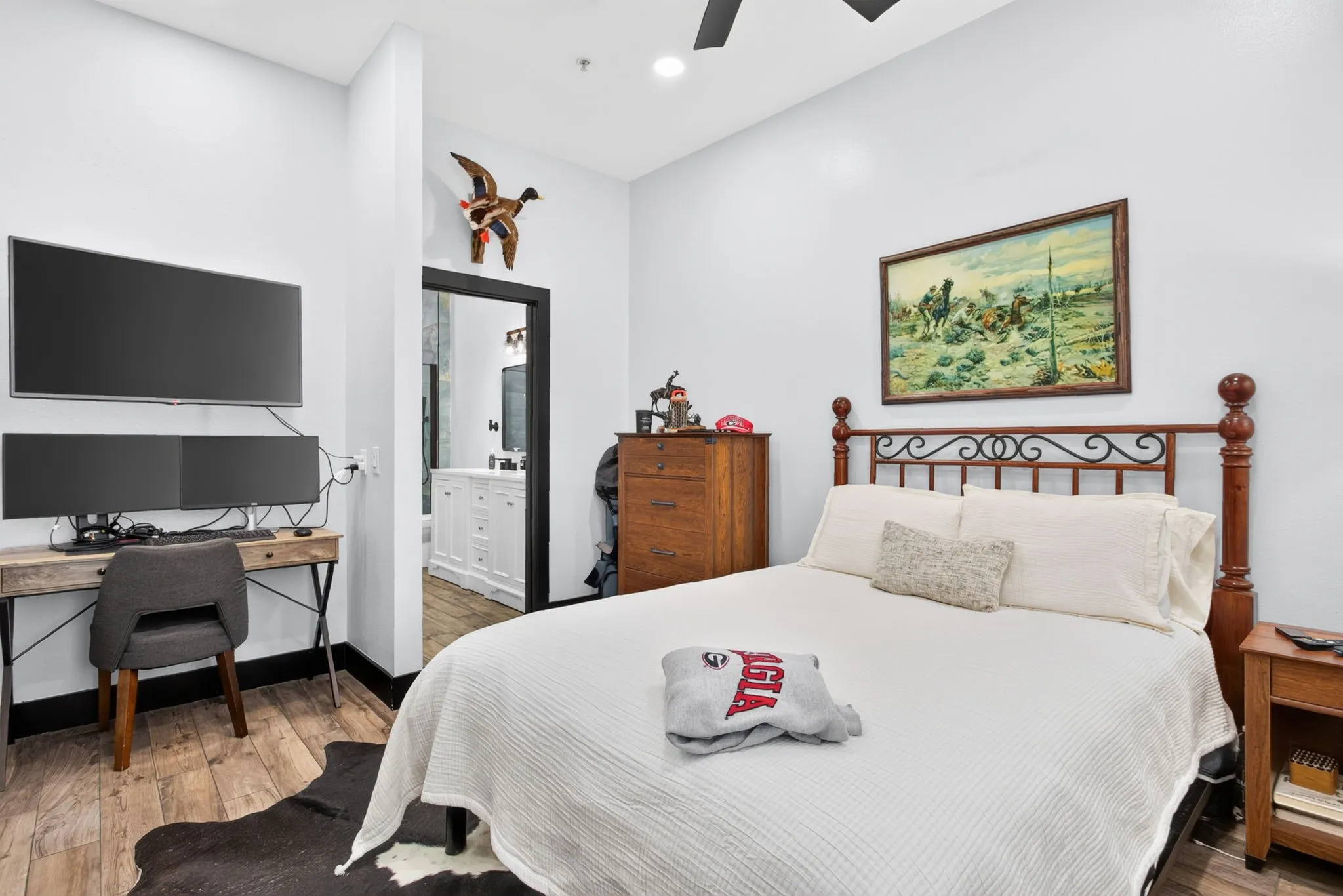 Interior room featuring wood-finish flooring, white walls, and a ceiling fan