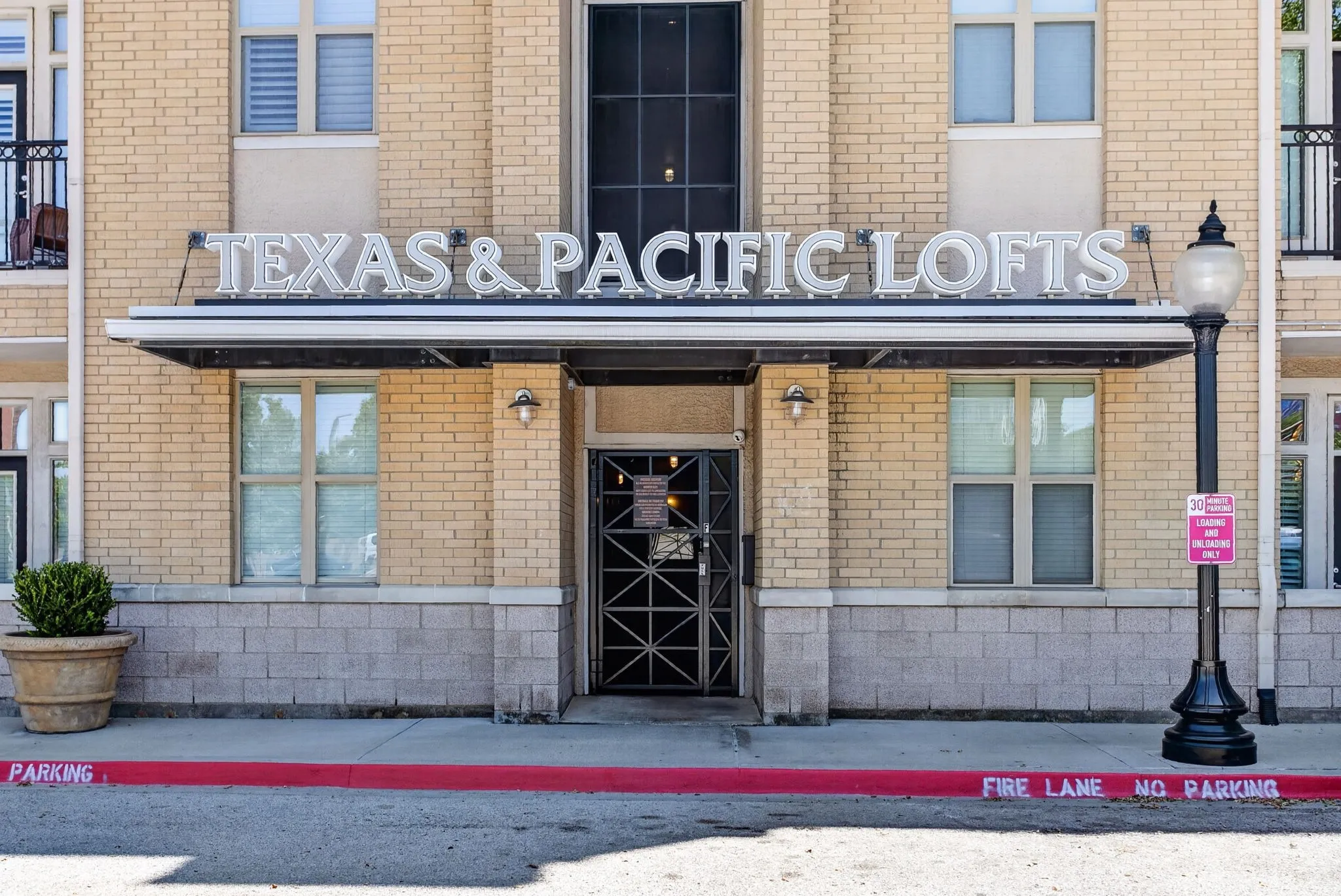Exterior facade featuring light-colored brick construction and a prominent "Texas & Pacific Lofts" sign
