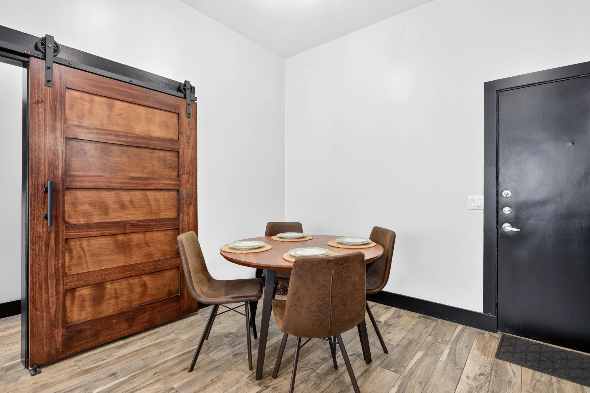 Wood-finish flooring throughout, featuring a rich wood panel barn door with black hardware