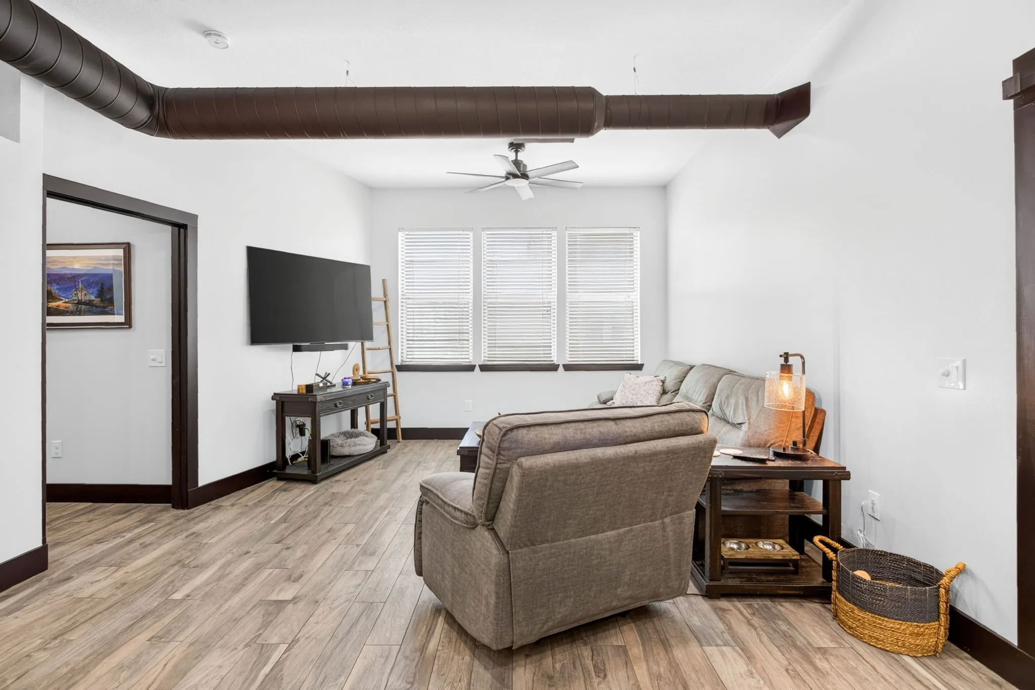 Open-concept living space with wood-finish flooring, white walls, and dark trim
