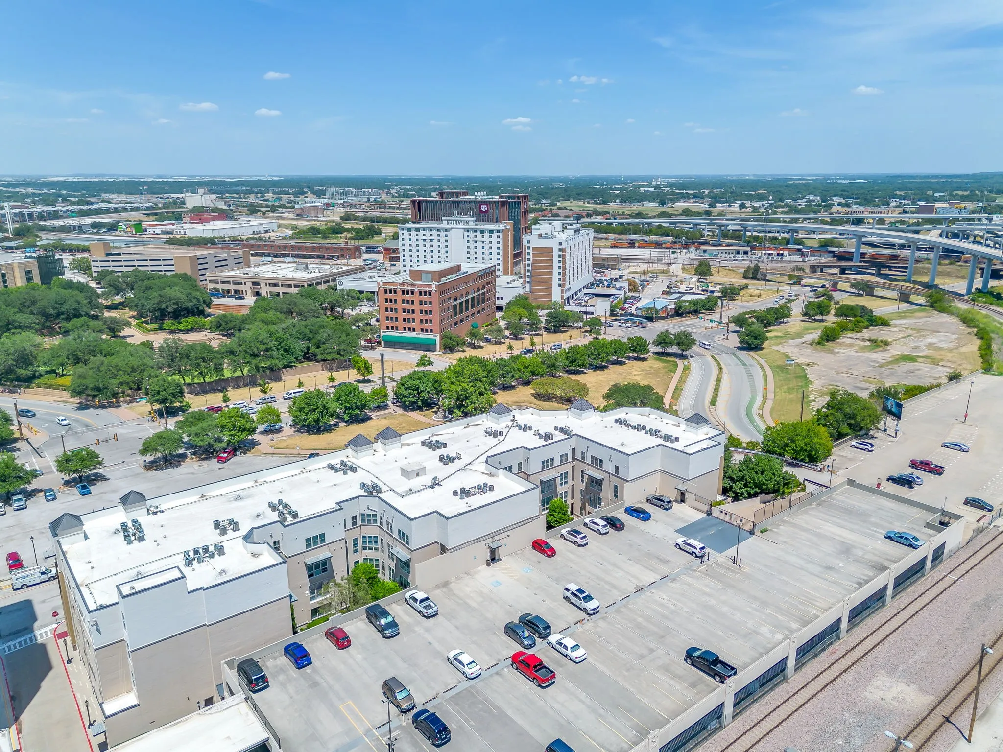 Aerial perspective showcasing a multi-story building with a light-colored roof and a visible parking structure