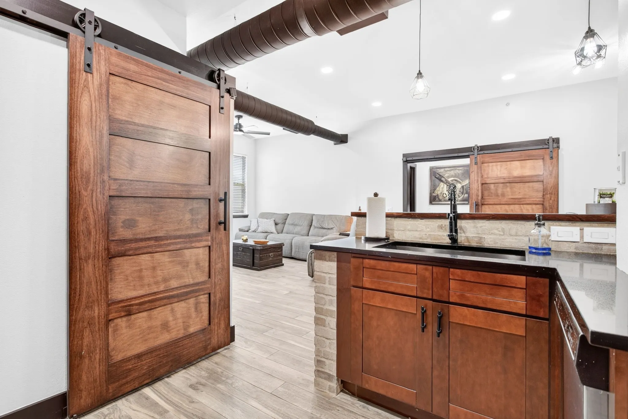 Wood-finish barn door entry featuring a dark metal track and hardware