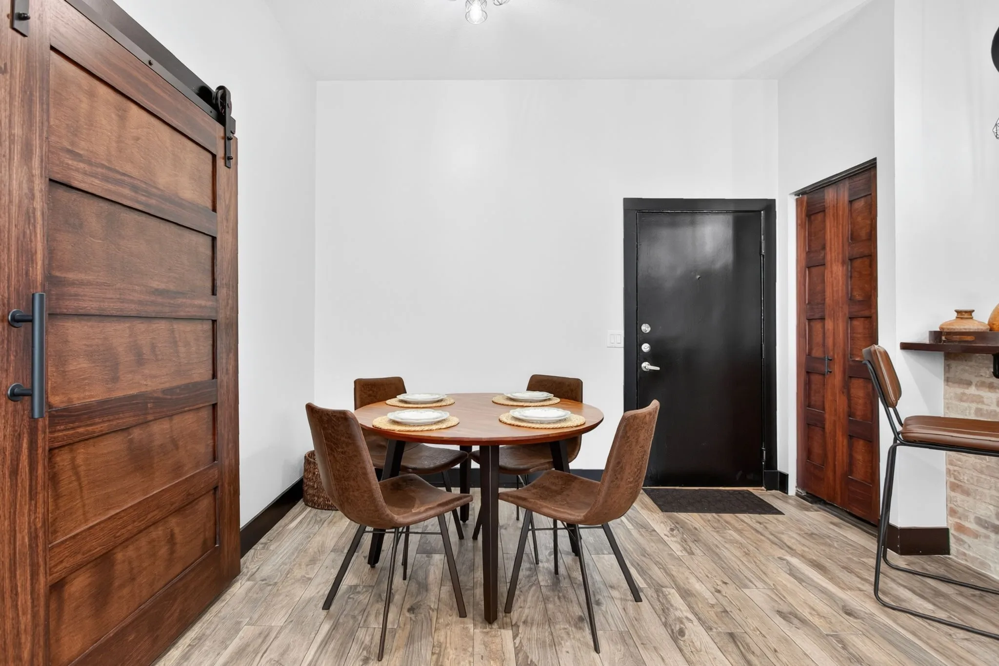 Dining area featuring wood-finish flooring, a dark wood barn door with black hardware, and a dark entry door