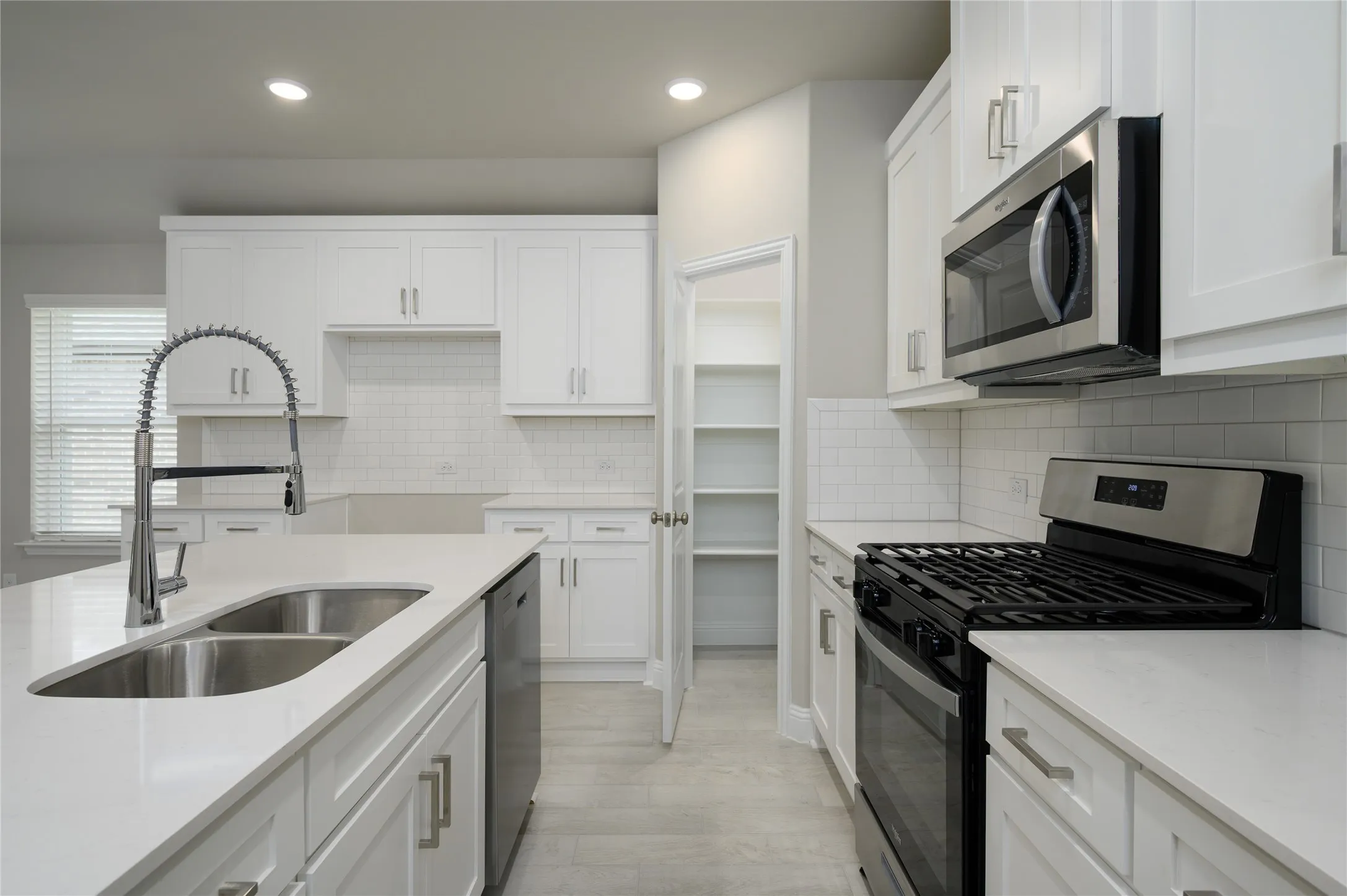 Kitchen featuring recessed lighting, a sink, light wood-style floors, white cabinets, and appliances with stainless steel finishes