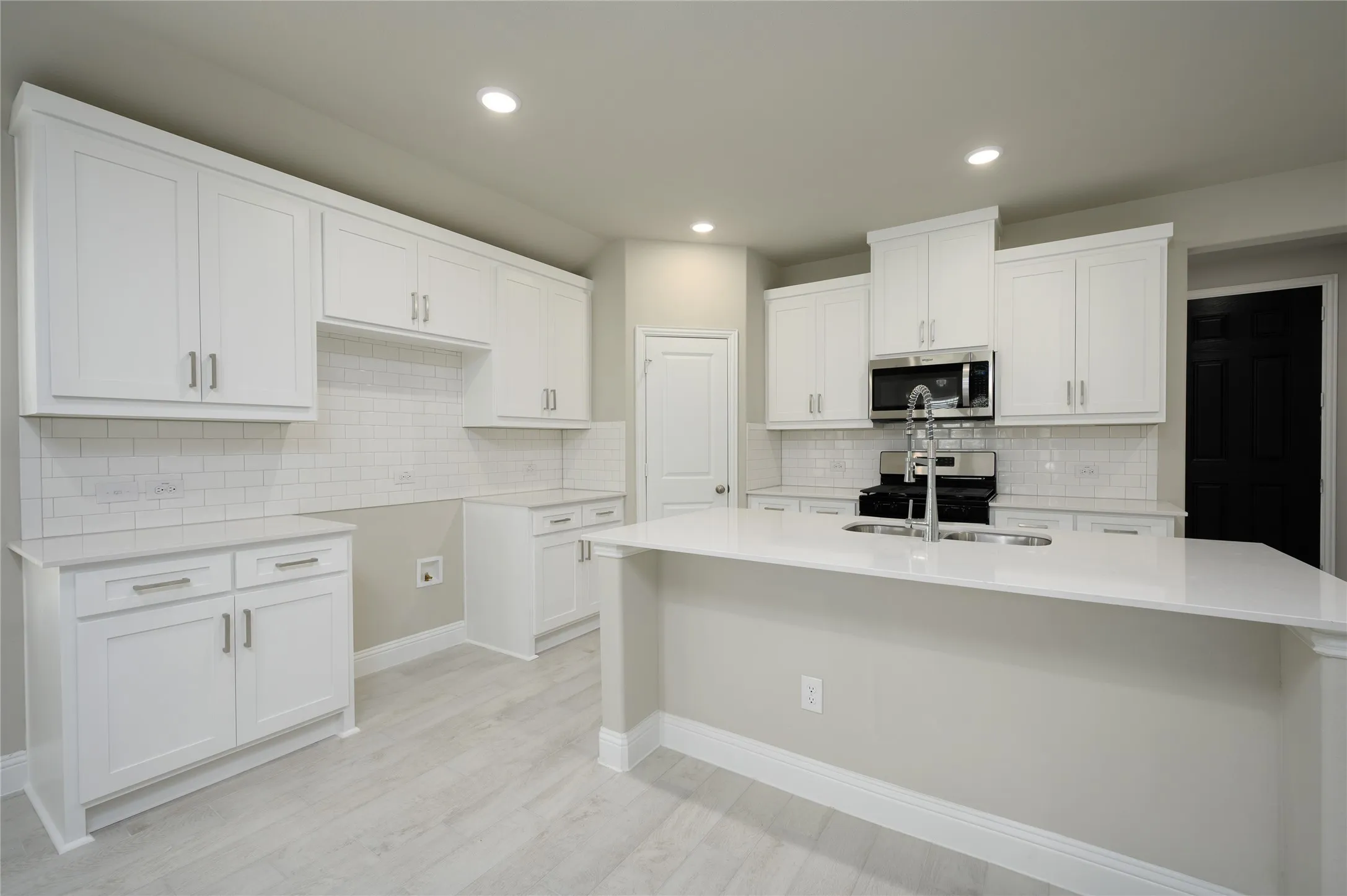 Kitchen featuring a sink, an island with sink, backsplash, and stainless steel appliances