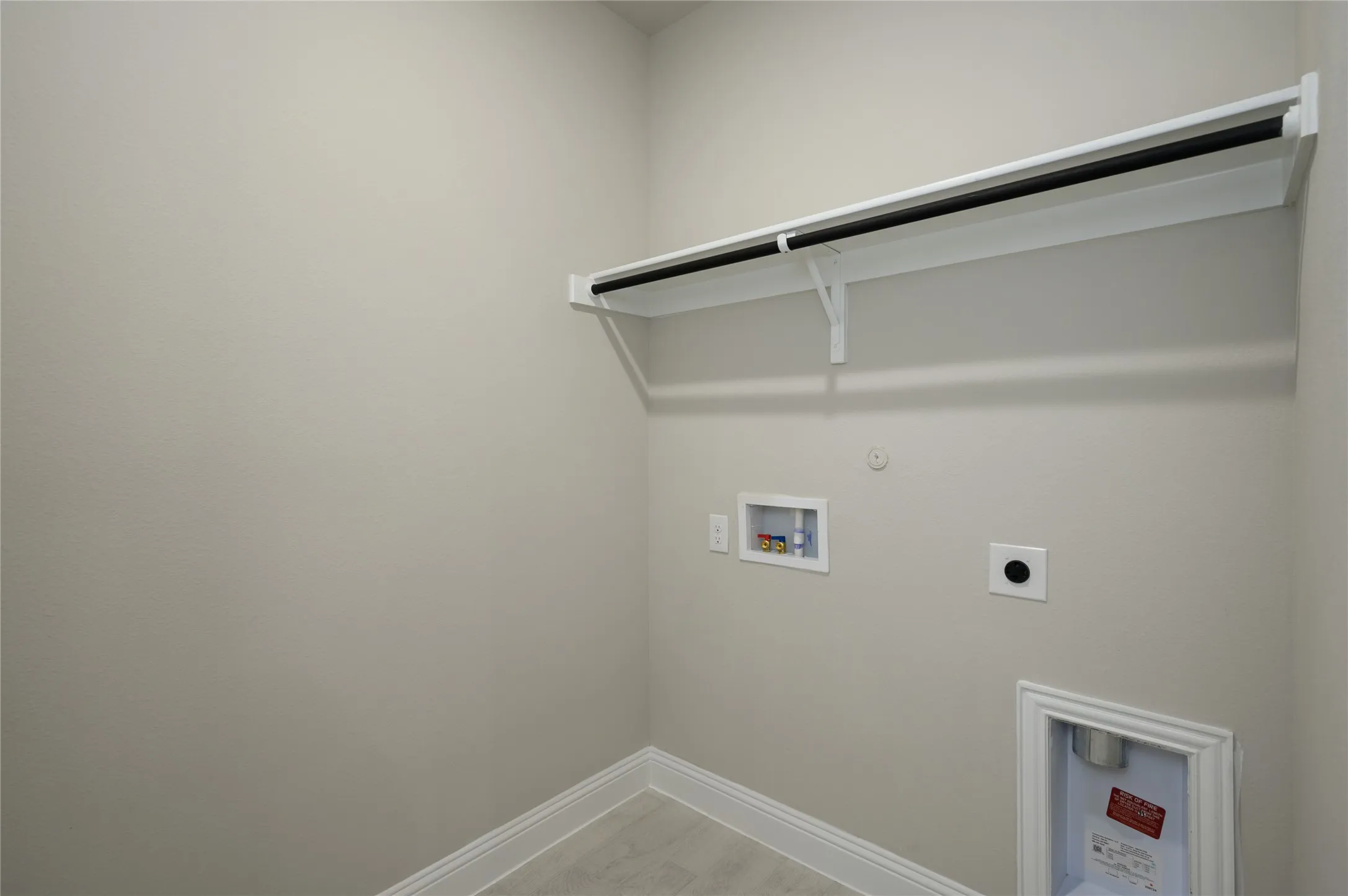Washroom with hookup for an electric dryer, hookup for a gas dryer, washer hookup, laundry area, and baseboards