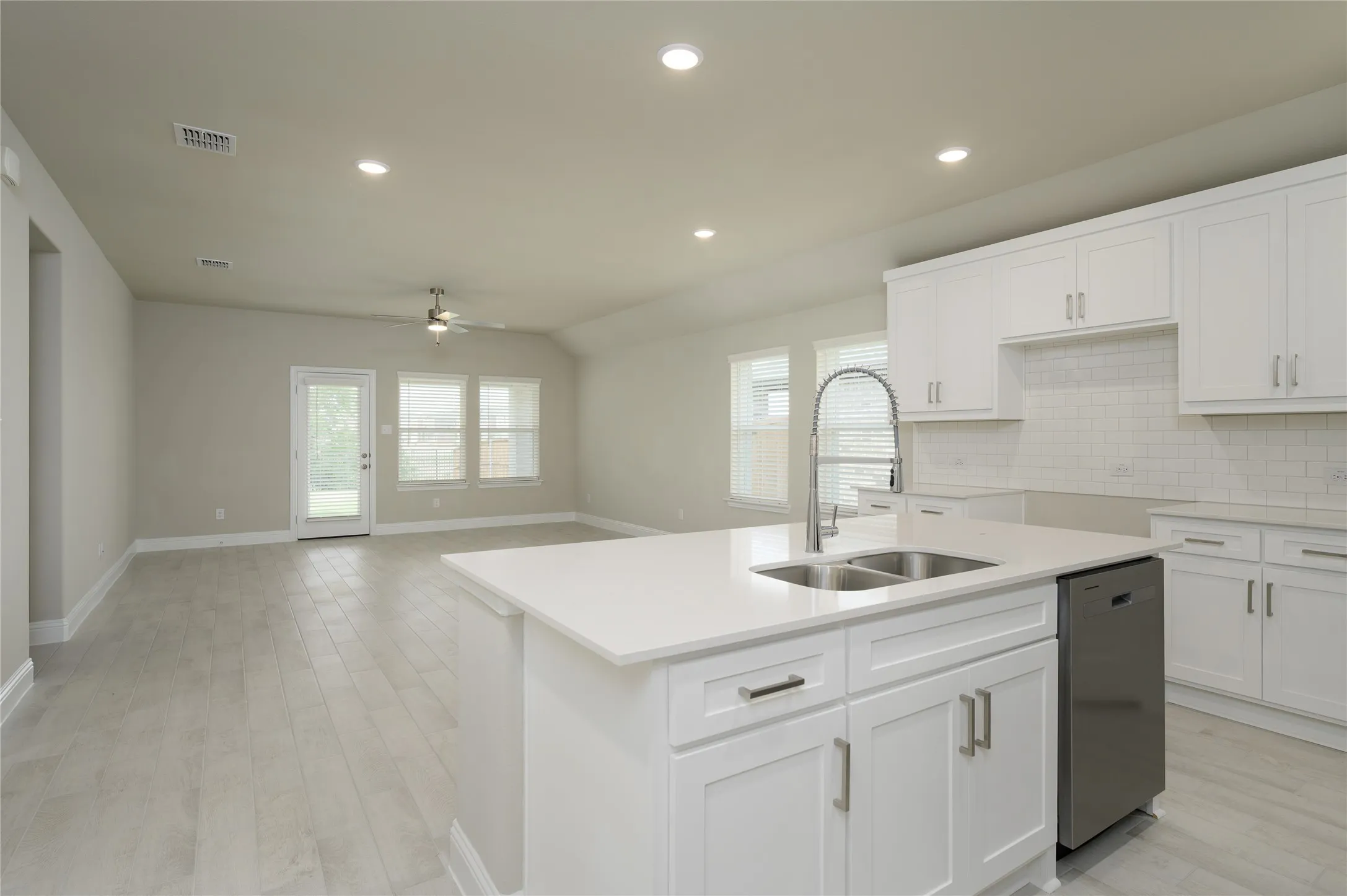 Kitchen with tasteful backsplash, a sink, visible vents, dishwasher, and a ceiling fan