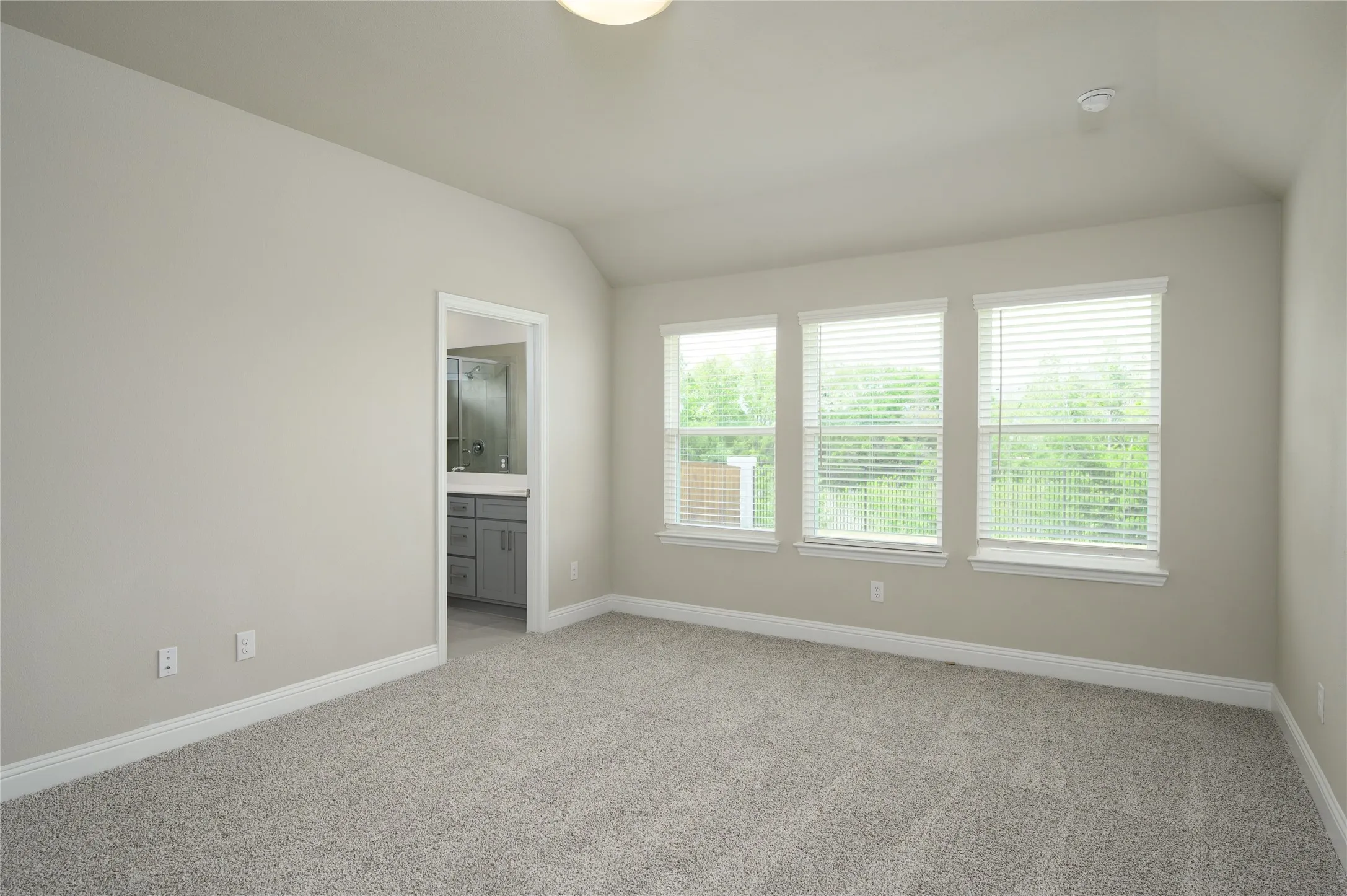 Spare room with baseboards, light carpet, and lofted ceiling