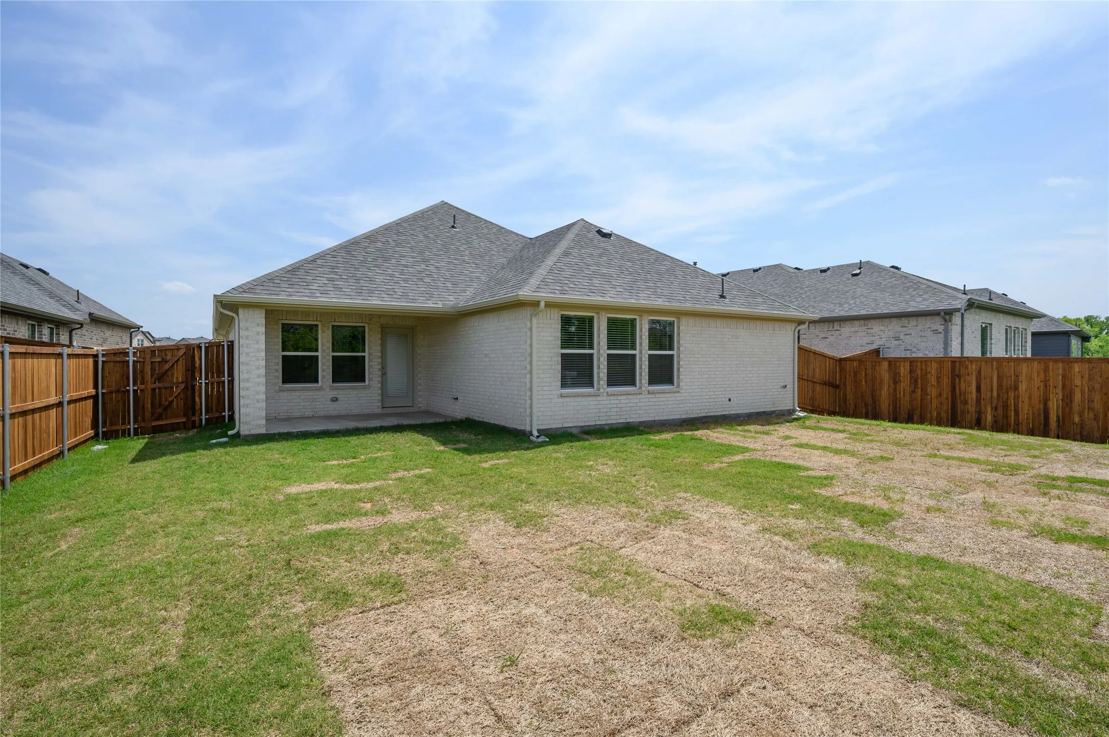 Back of house with a patio area, a yard, a fenced backyard, brick siding, and roof with shingles