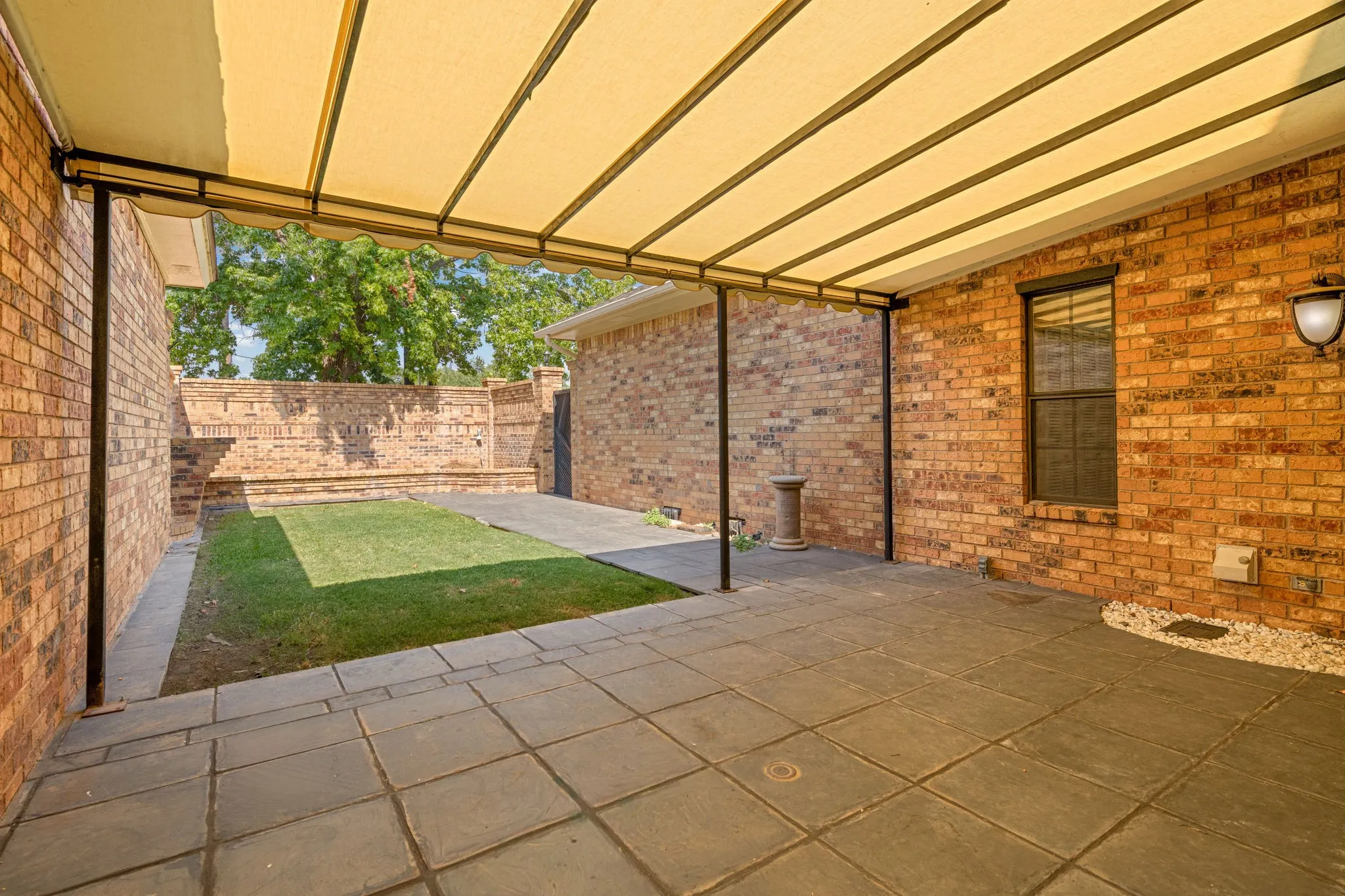 Canopy covered back patio.  Brick planters.  Gutters.  Side gate to rear entry garage.