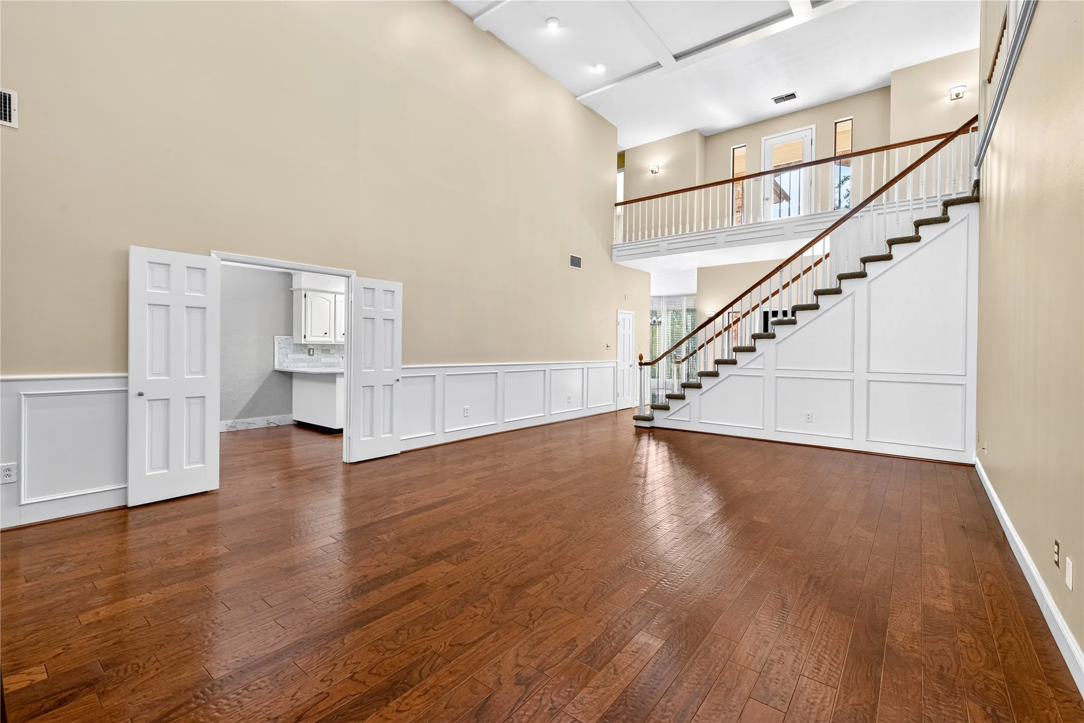Soaring ceilings and natural light from the upstairs balcony door and side windows add to this spacious living room.