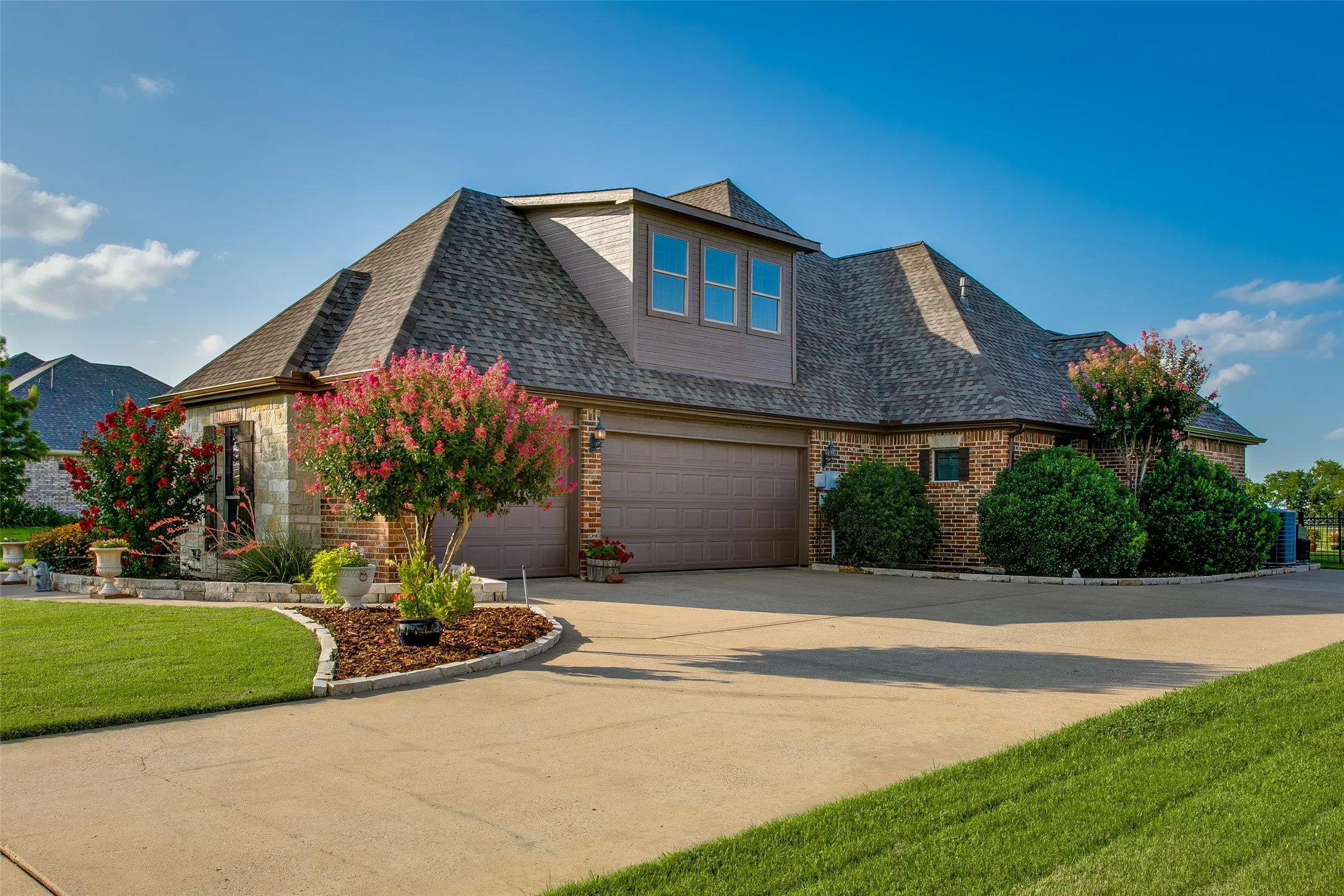 Side of home featuring 3 car attached garage and expanded driveway for additional parking