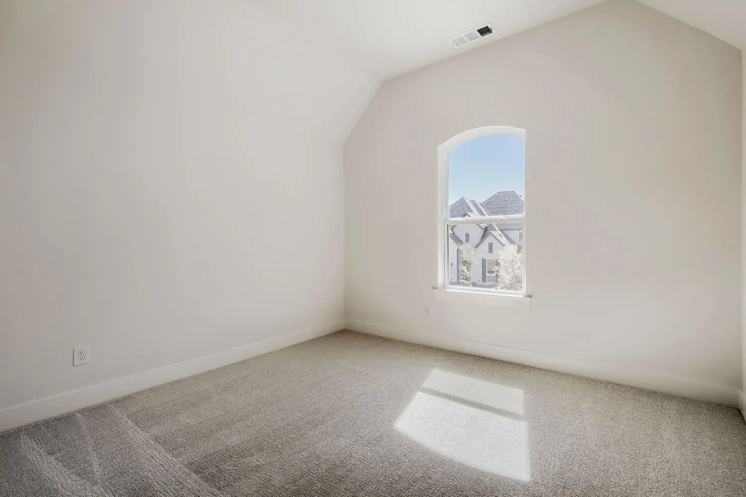 Vaulted ceiling with an arched window, soft gray carpeting, and light-toned walls
