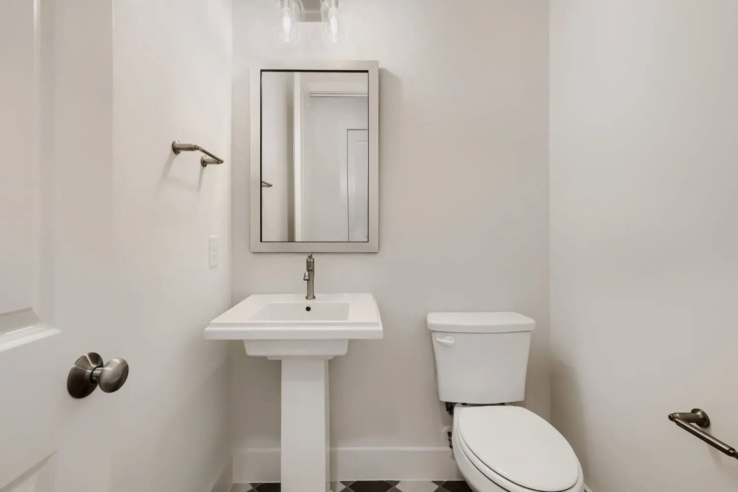 Pedestal sink with a polished chrome faucet, framed mirror, and a classic white toilet