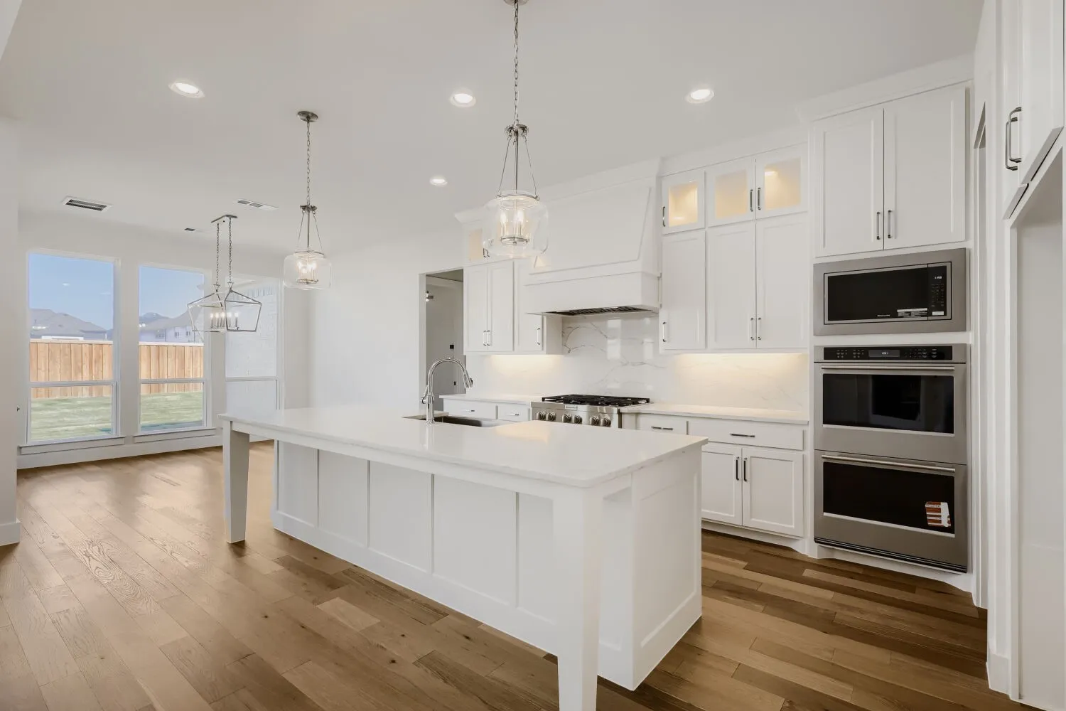 Gourmet kitchen with white cabinetry, stainless steel appliances, a large center island, pendant lighting, and wood-finish flooring