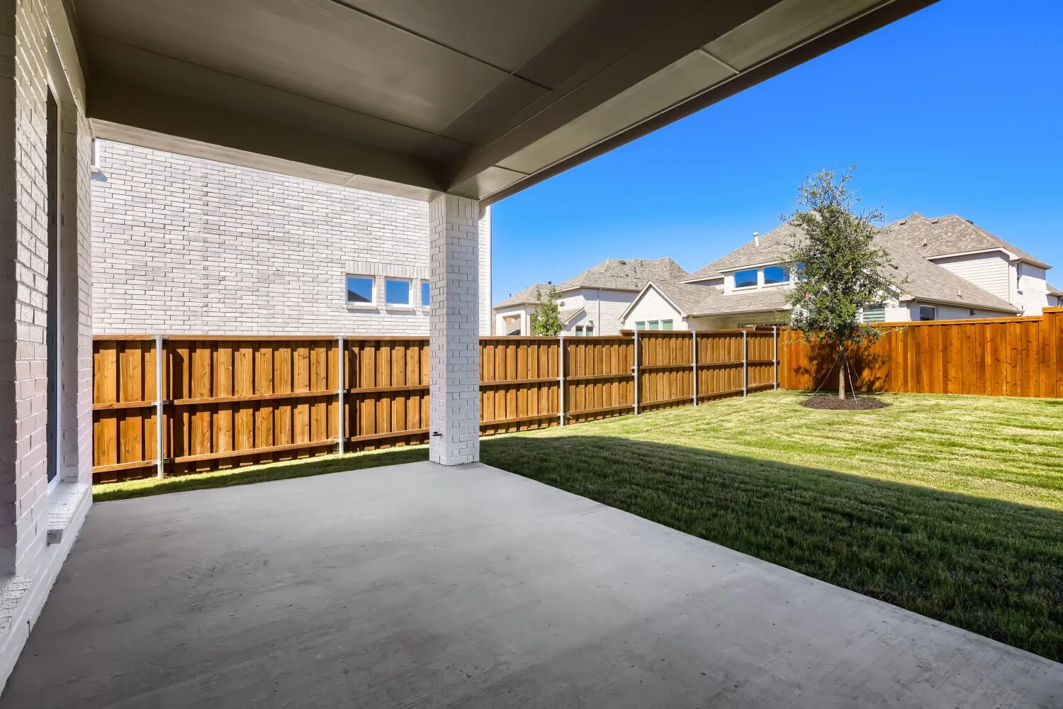Covered concrete patio with a white brick exterior