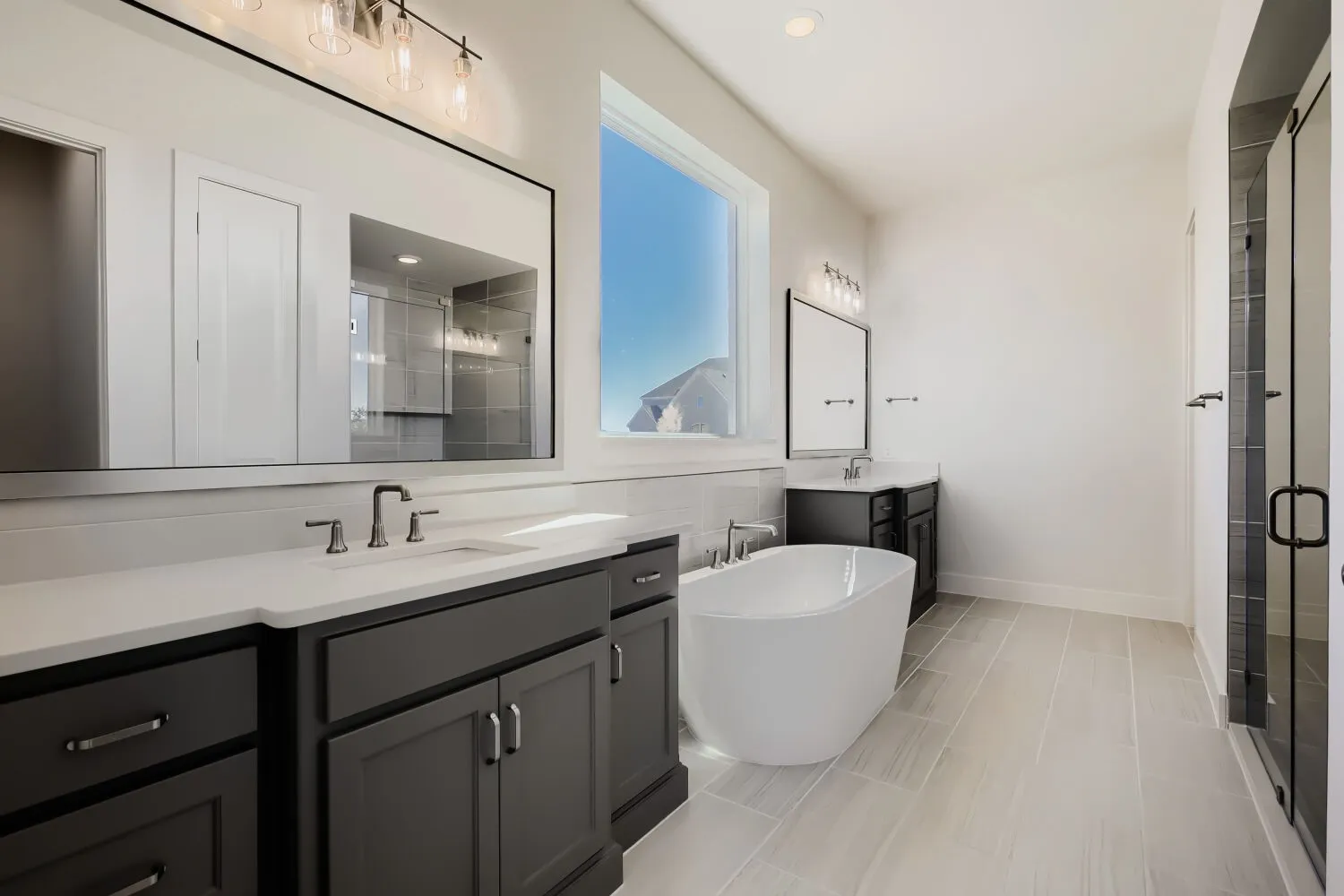 Dual vanity with quartz countertops, a freestanding soaking tub, large window, and tile flooring