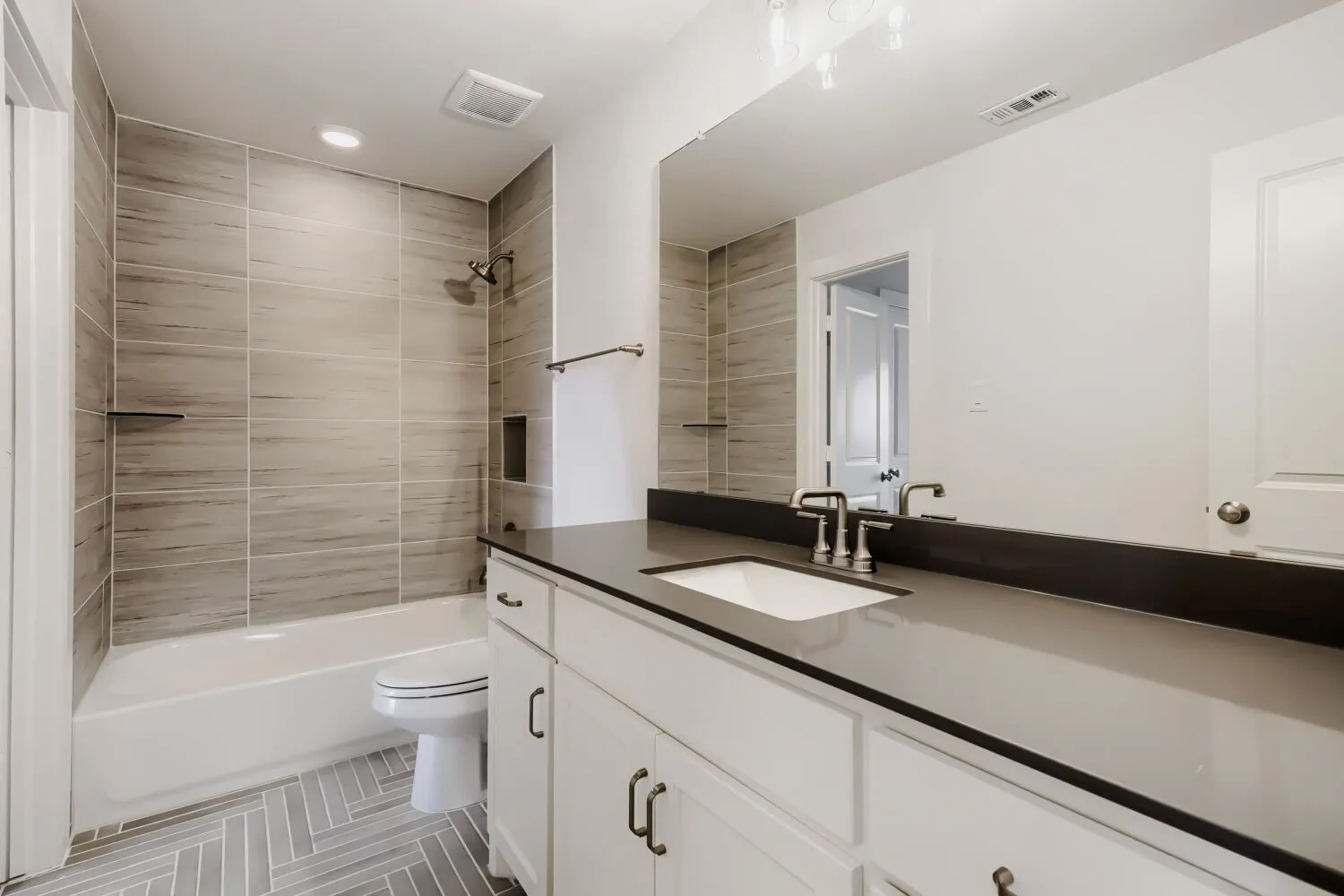 White vanity with dark countertop, undermount sink, and brushed nickel fixtures