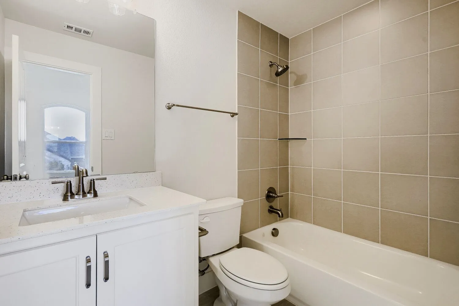 White vanity with integrated sink, speckled white countertop, and dark bronze-finish fixtures