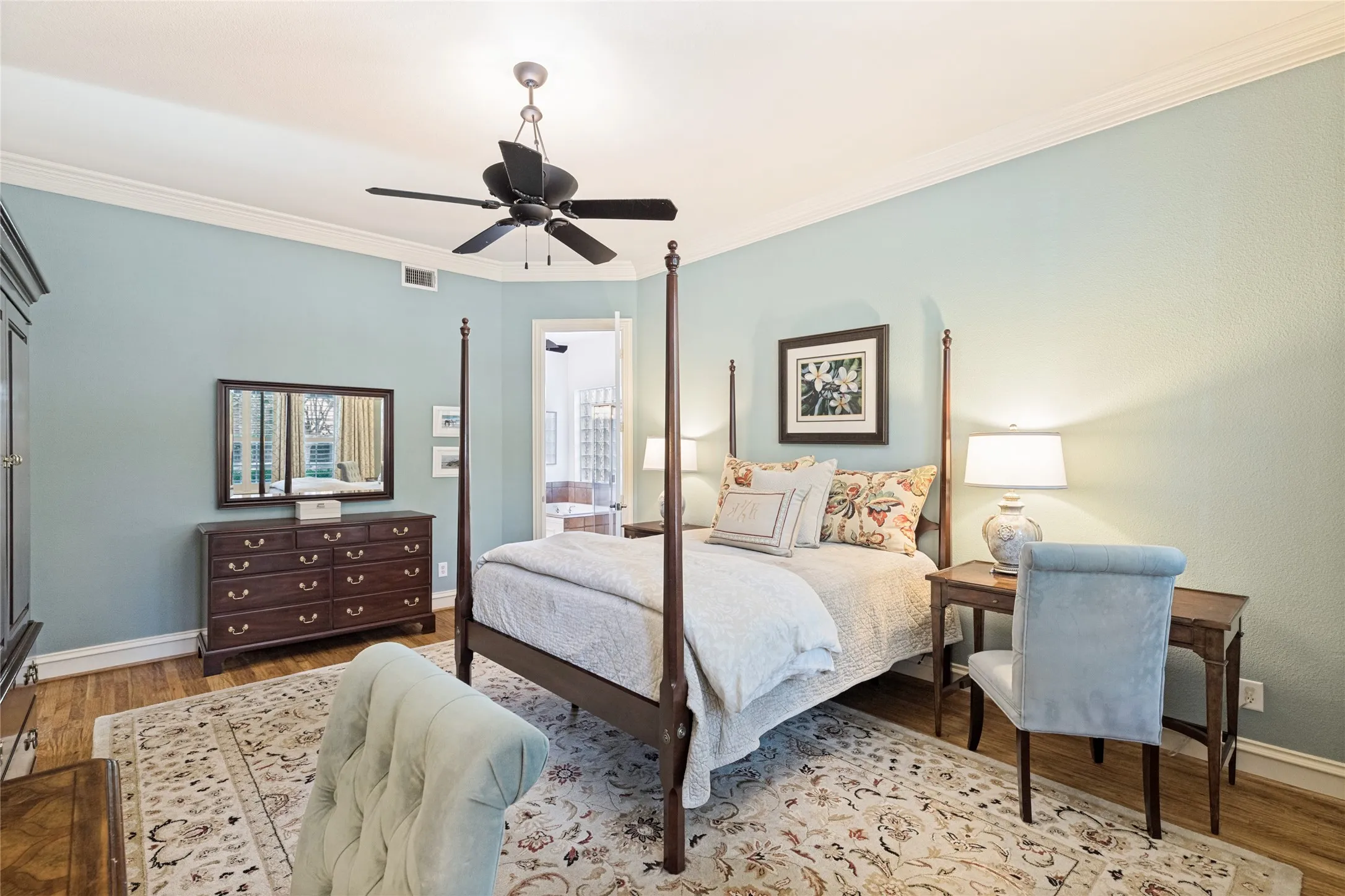 Primary bedroom offers hardwood floors, plantation shutters and lovely crown molding detail and en-suite bath