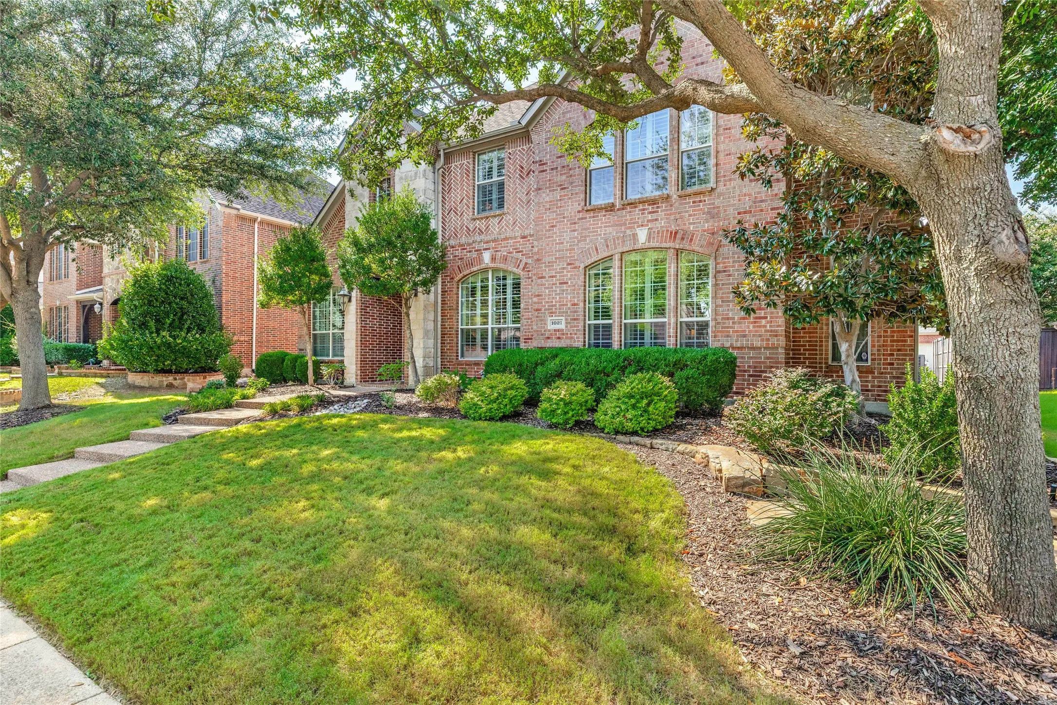 Mature trees and lovely landscaping and stone-lined flower beds