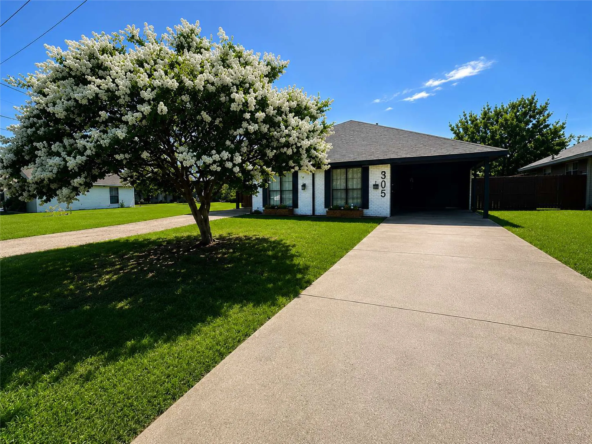 White brick exterior with black trim, a gabled roof, and a paved driveway