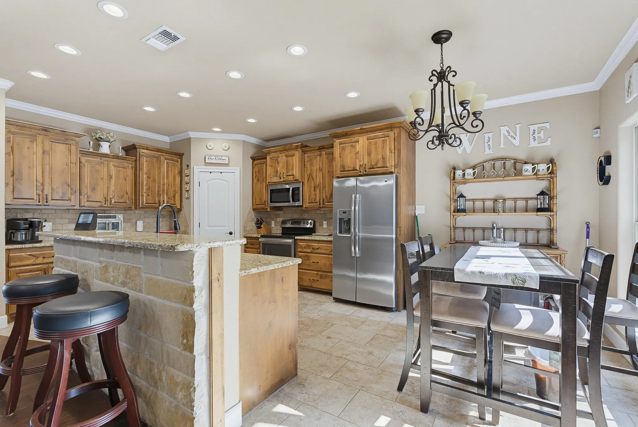Kitchen featuring a stone-clad breakfast bar, natural wood cabinetry, stainless steel appliances, recessed lighting, and tile flooring