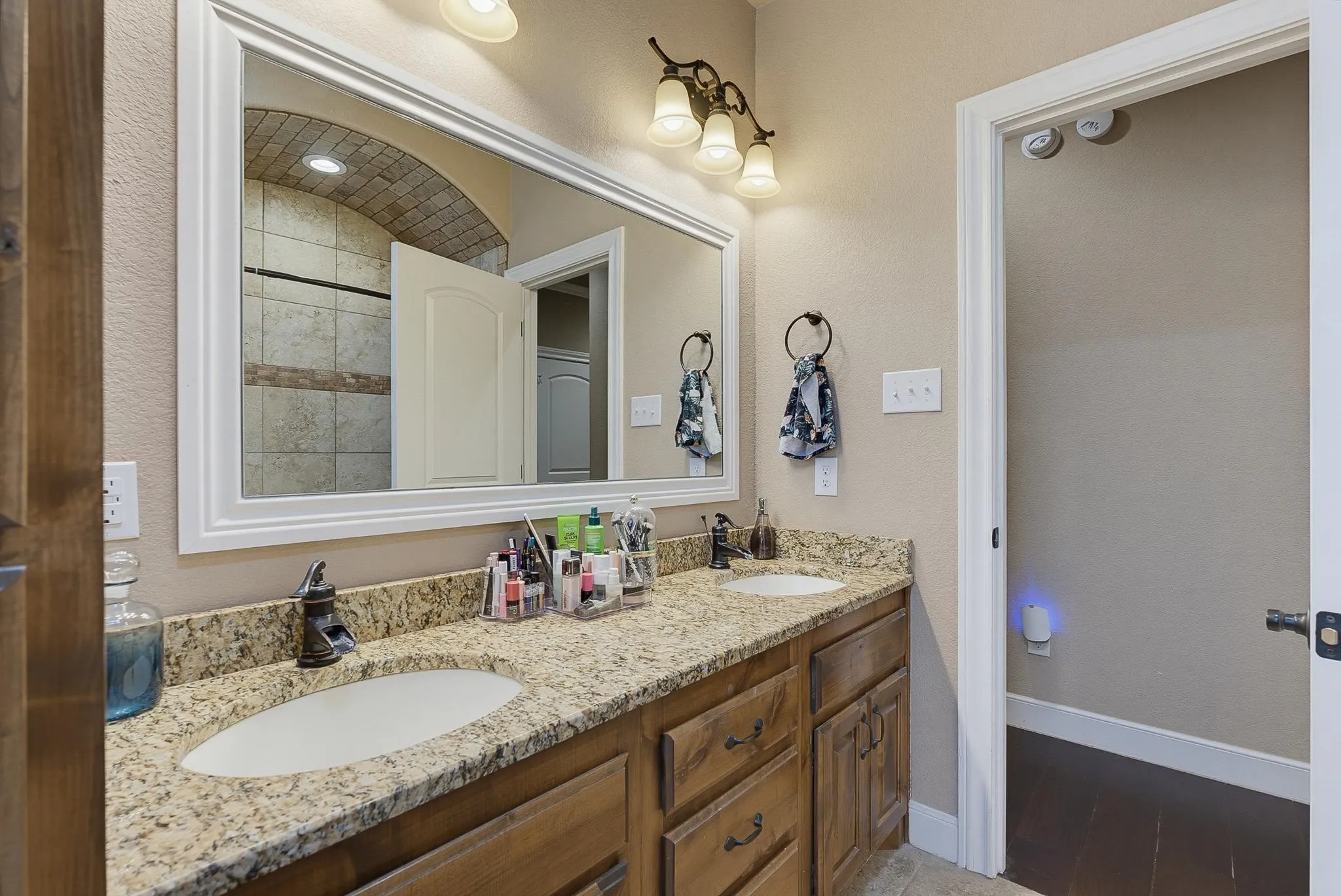 Bathroom featuring a double vanity with granite-style countertops, integrated oval sinks, and dark wood cabinetry