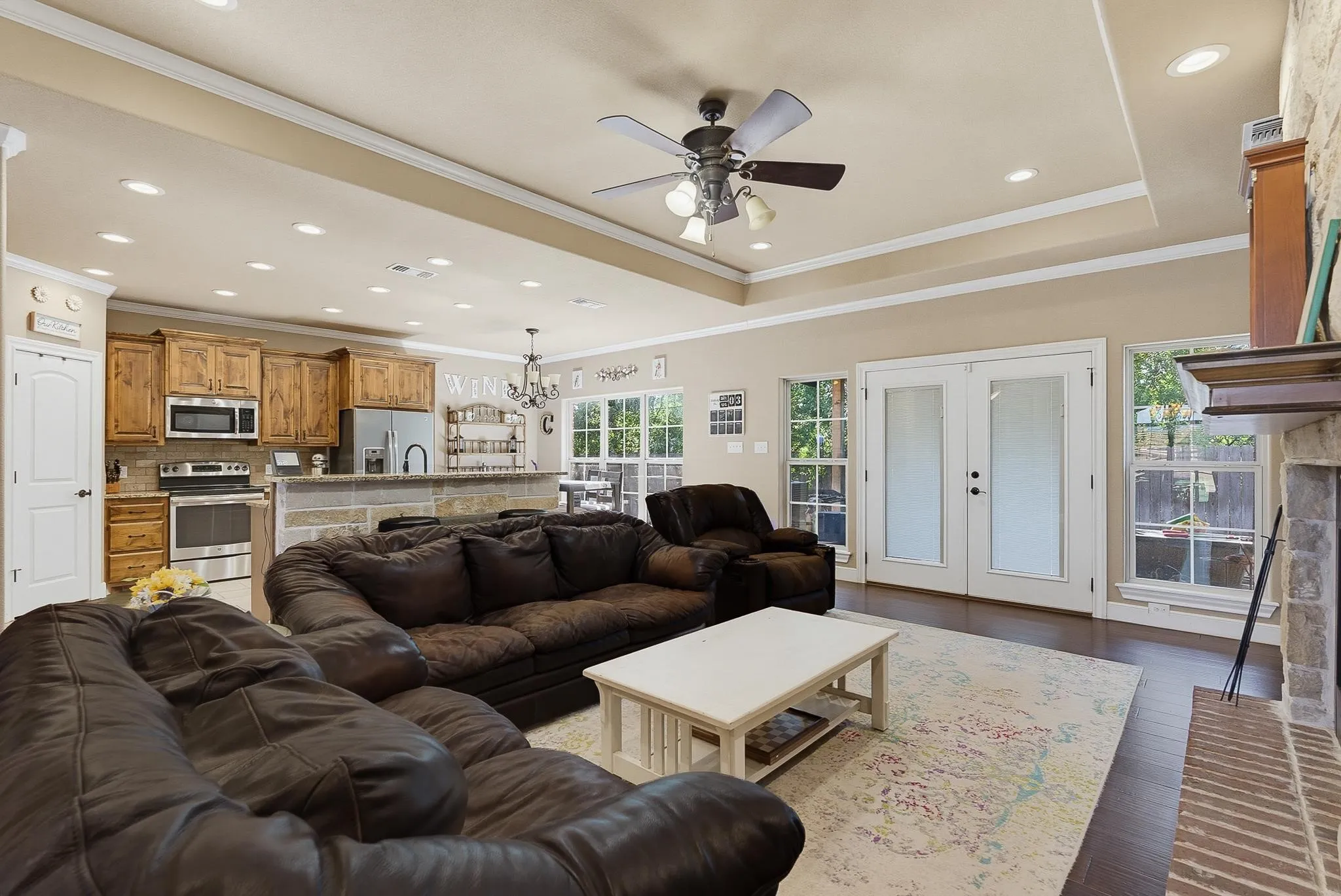 Expansive living area featuring wood-finish flooring and a stone-faced fireplace with a wood mantel