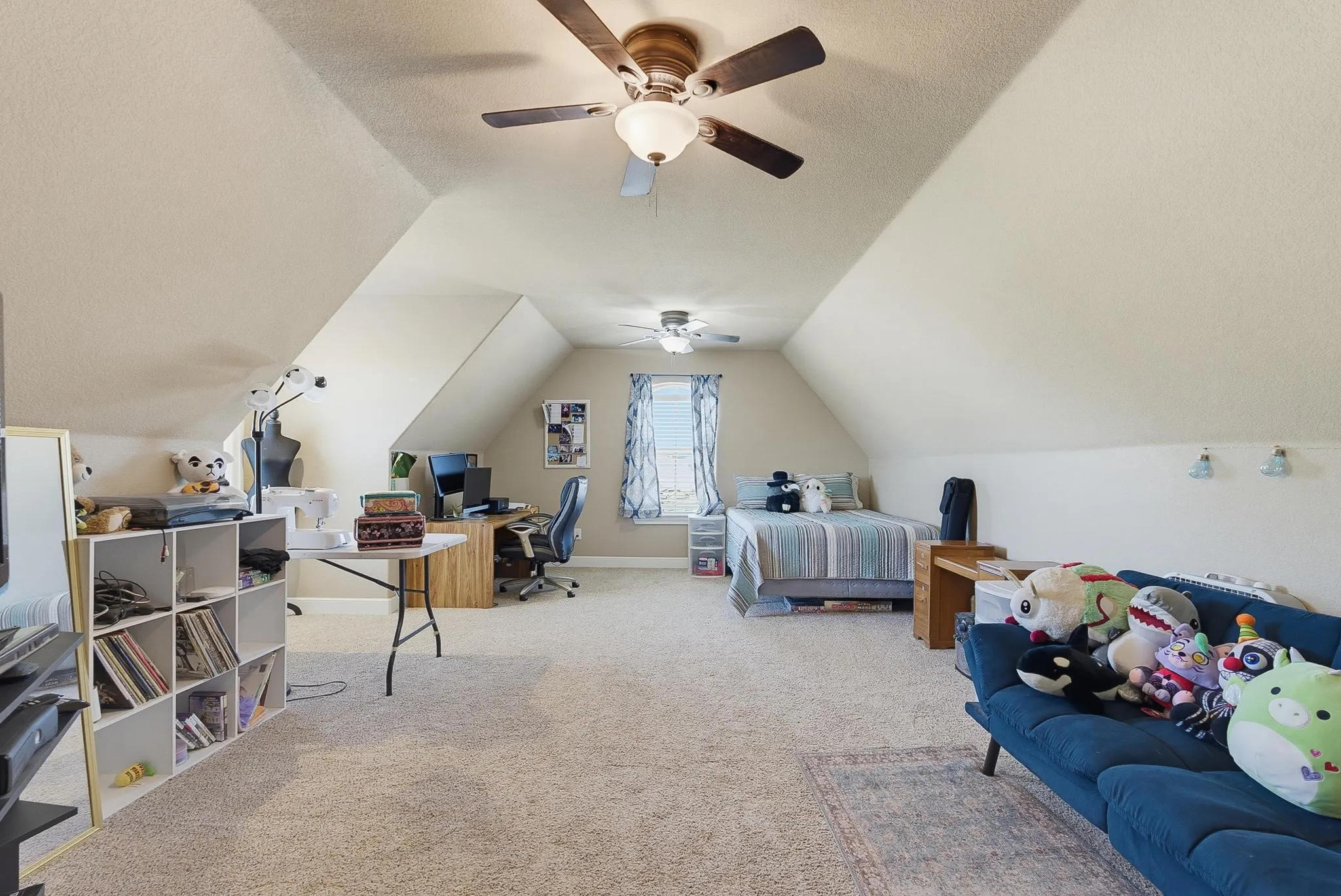 Expansive bonus room featuring sloped ceilings, two ceiling fans with integrated lighting, and neutral carpet flooring