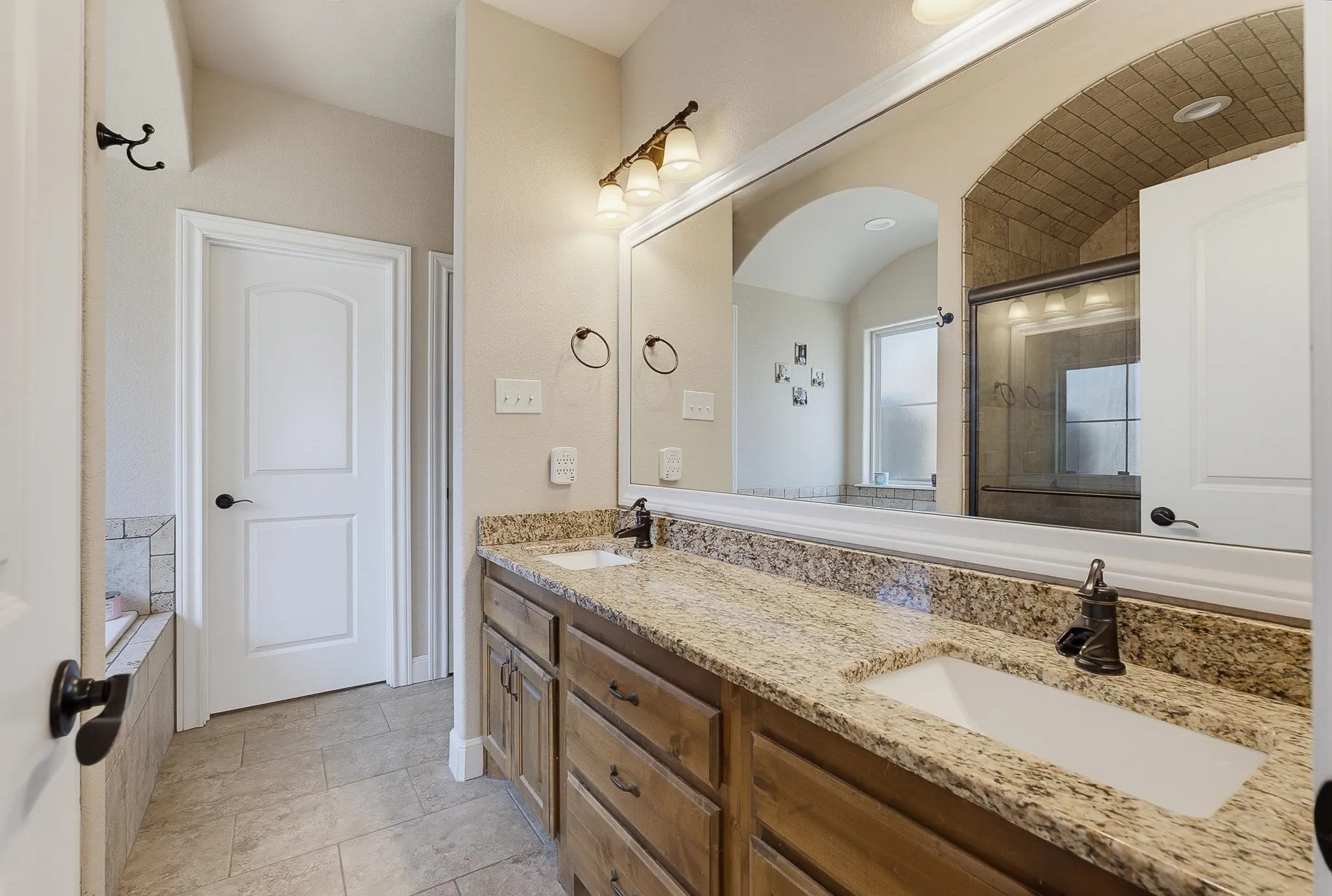 Double vanity with granite-style countertops and undermount sinks, featuring dark bronze-finish fixtures