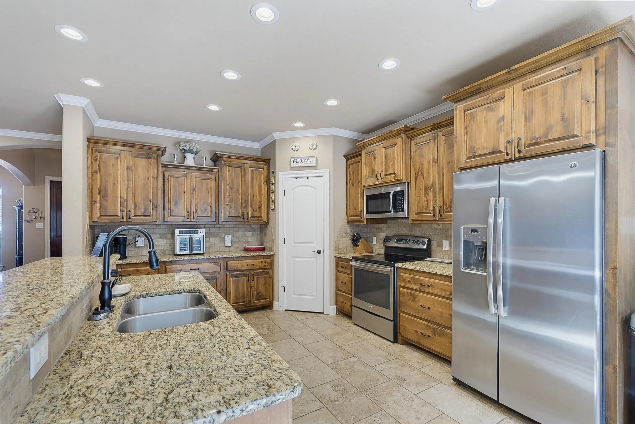Kitchen featuring wood cabinetry, granite countertops, stainless steel appliances, tile flooring, and recessed lighting